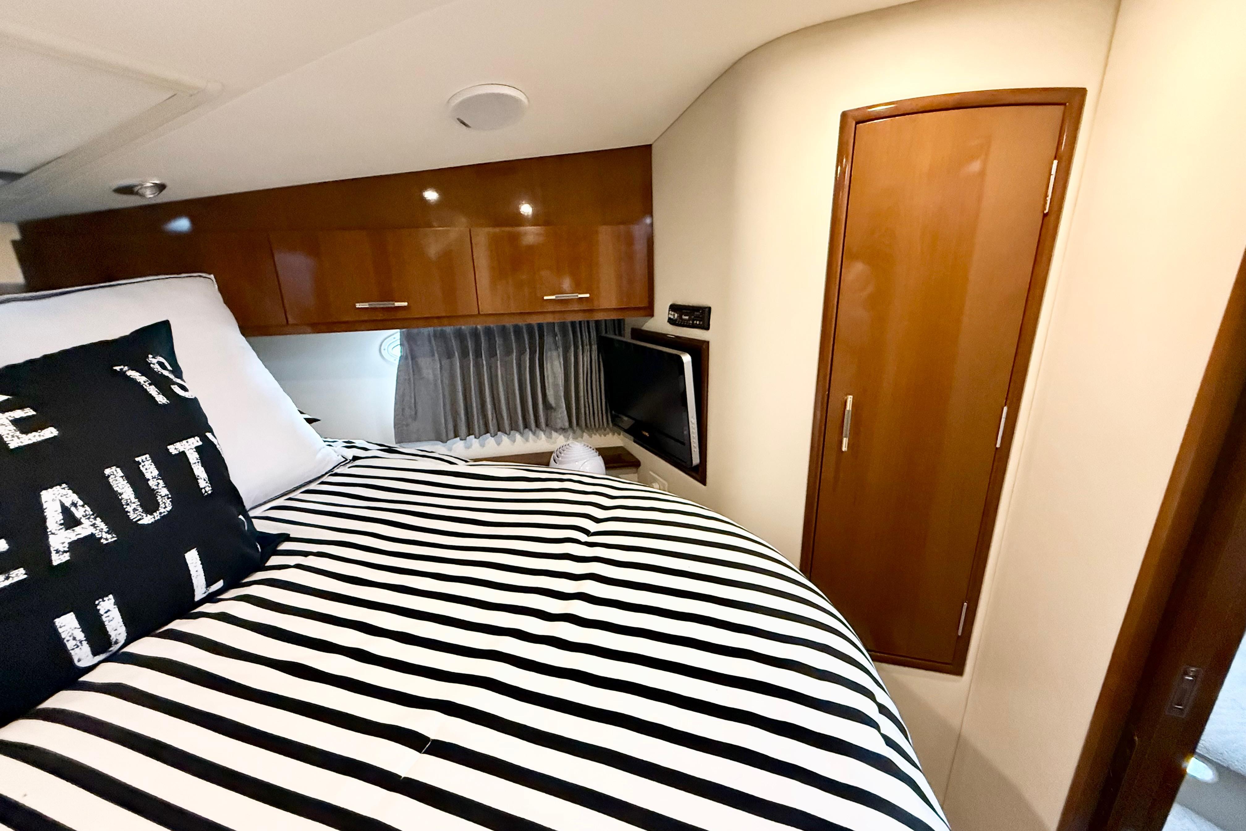Interior of 2007 Carver 36 Sedan with striped bedding and wooden cabinetry.
