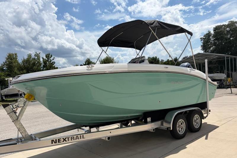 2026 Hurricane SunDeck Sport 2050 OB boat on trailer under blue sky.