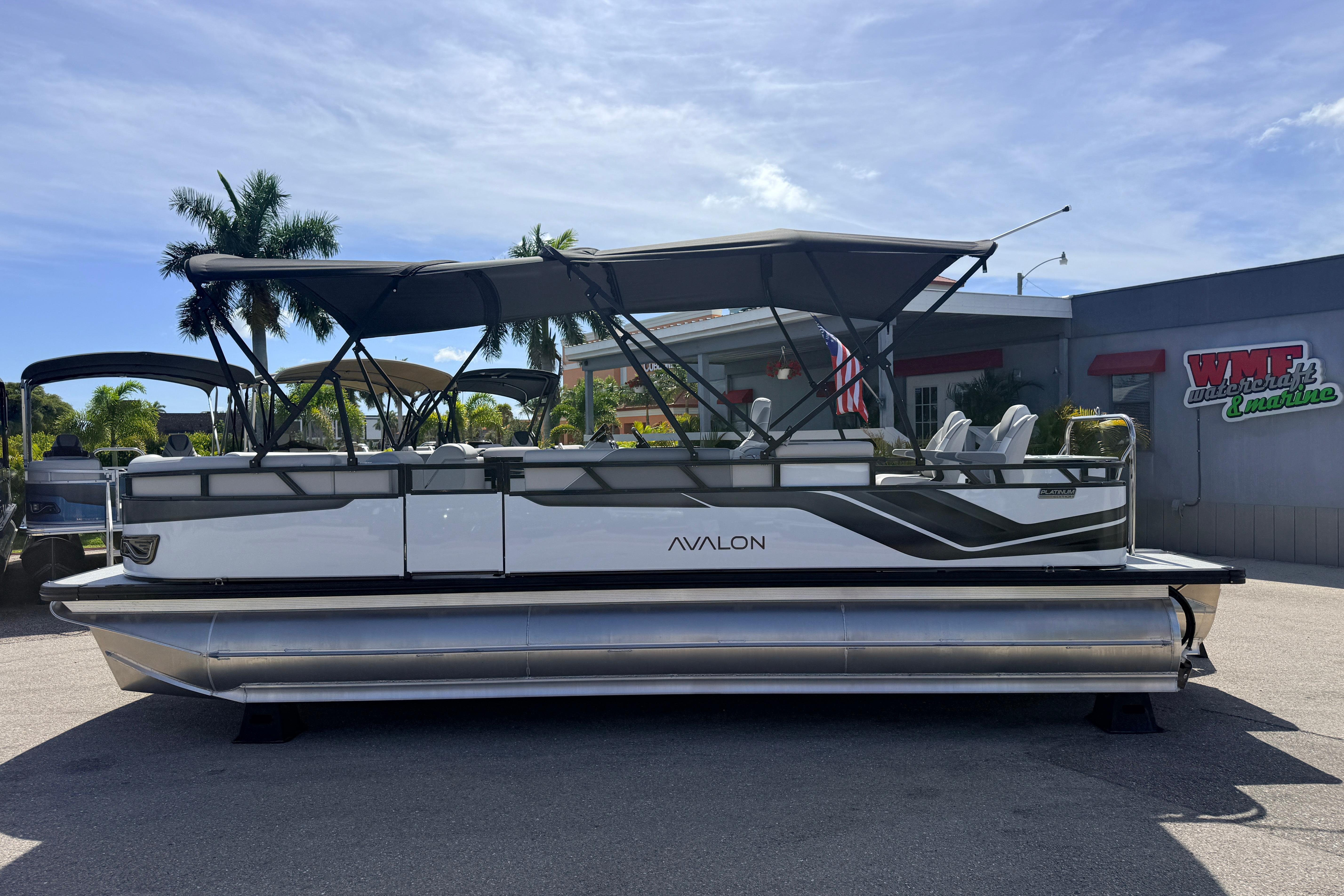 2026 Avalon 2385 Venture 85 Tri Toon boat with canopy, parked outdoors.
