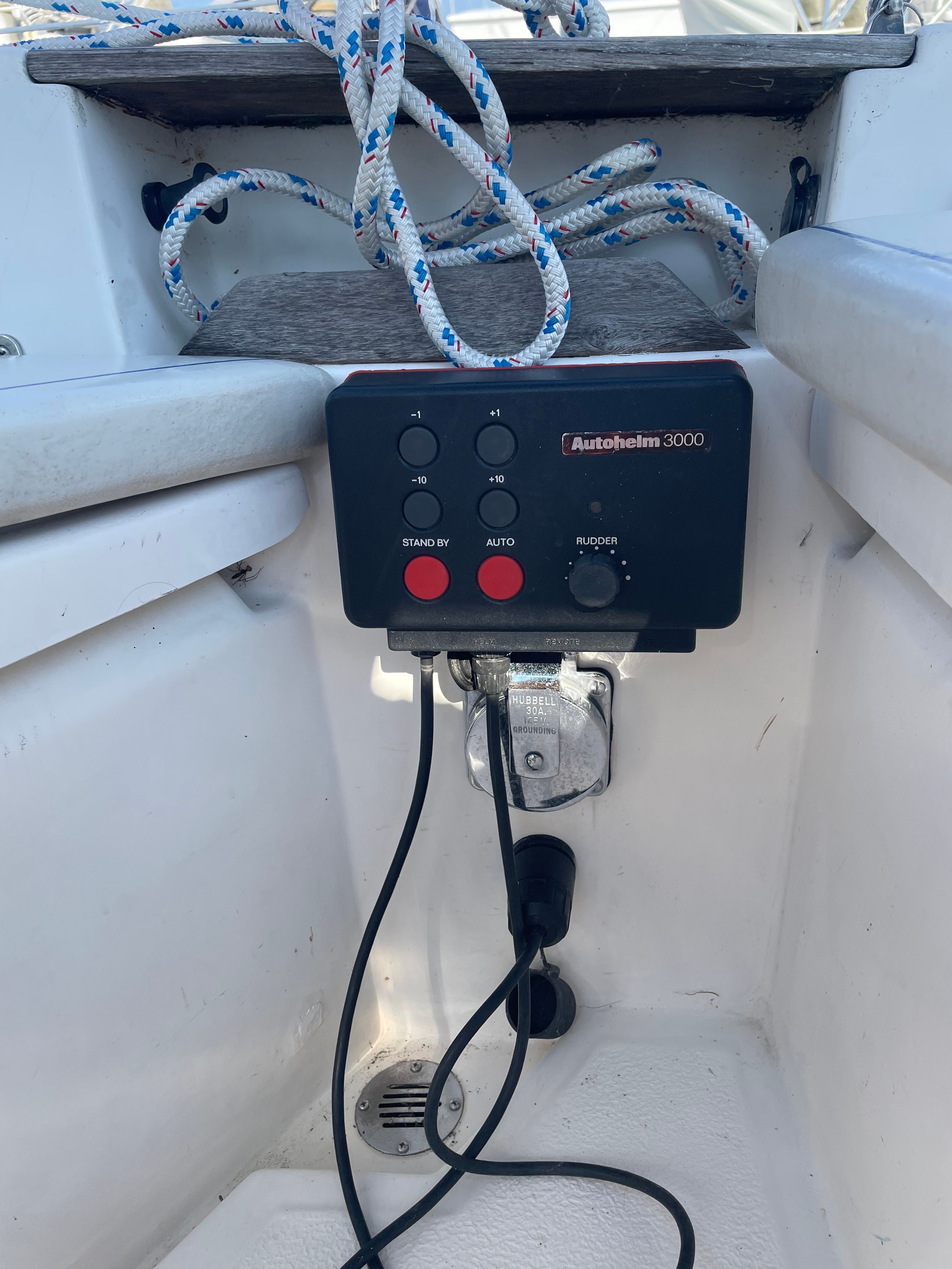Autopilot control on a boat with ropes in the background.