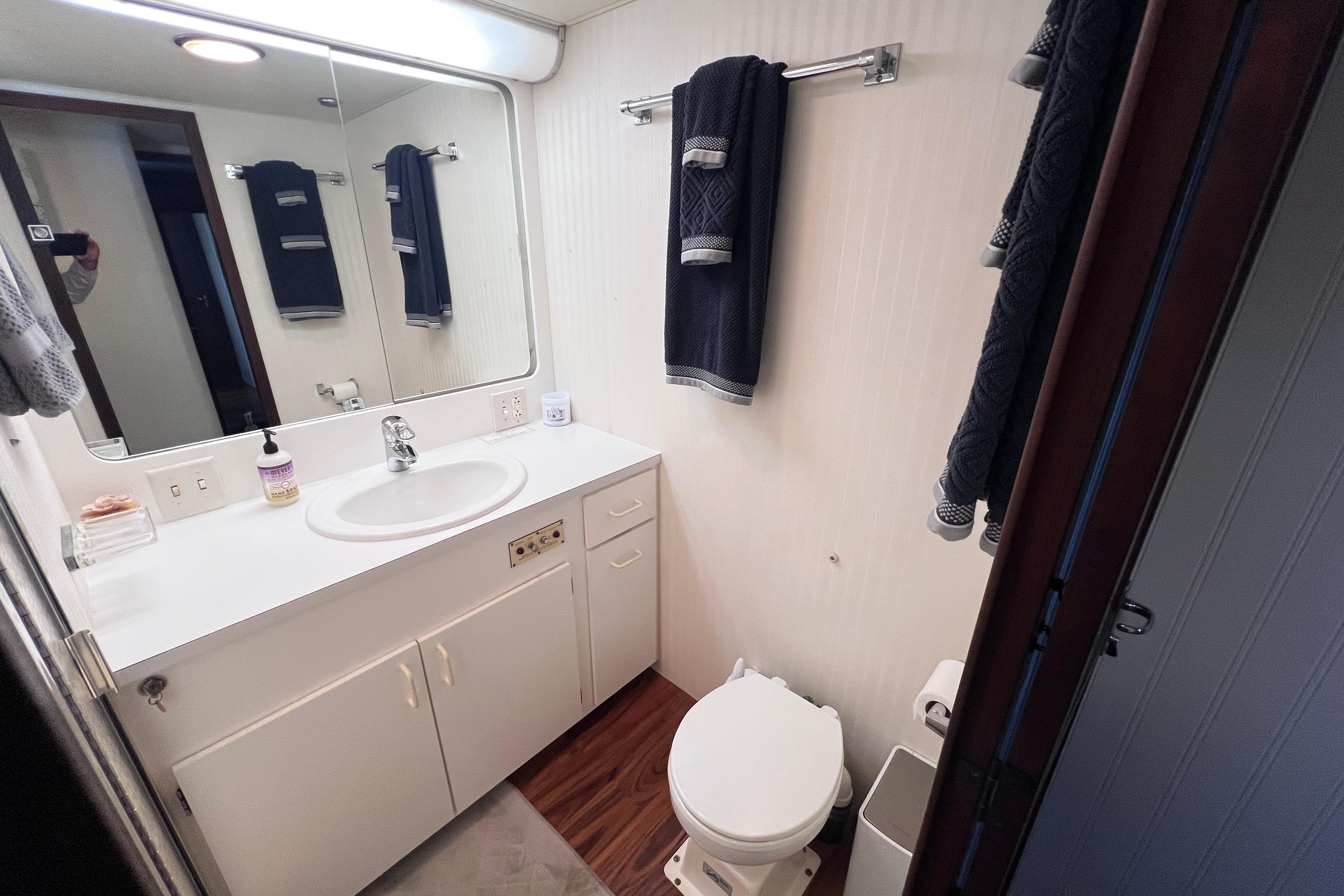 Bathroom interior of 1987 Hatteras 70 Cockpit Motor Yacht, featuring sink and toilet.