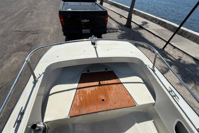 1990 Boston Whaler 17 Newport boat on trailer near waterfront, with pickup truck in background.