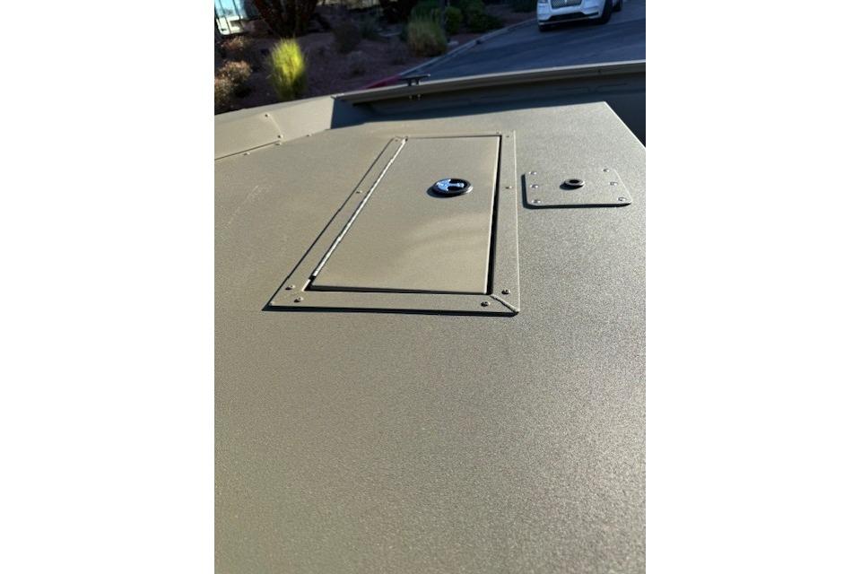 2026 Tracker Grizzly 1648 SC boat deck with storage compartment in sunlight.