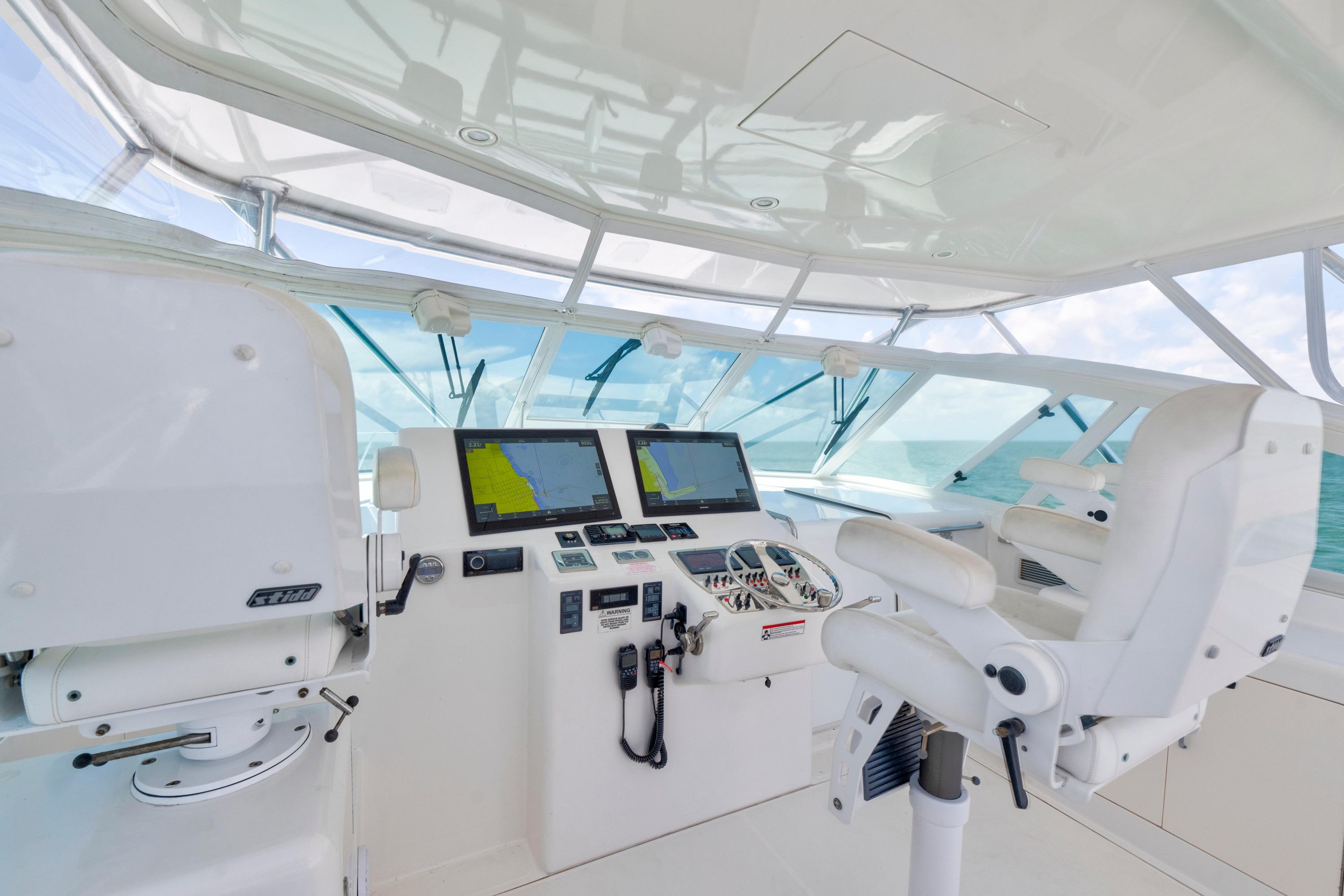 2010 Cabo 45 Express helm with navigation screens and white captain's chairs.