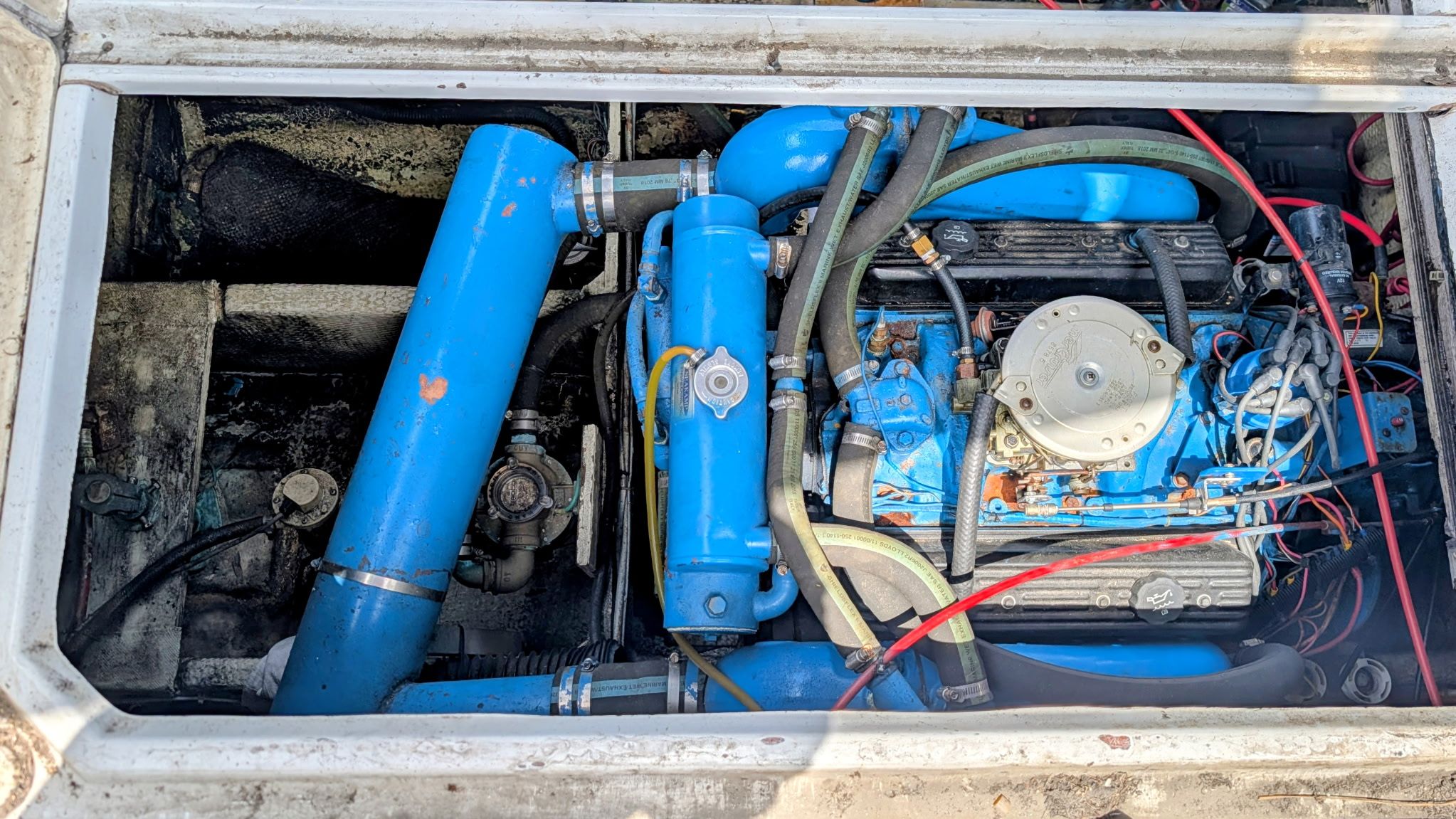 Engine compartment of a 1987 Chris-Craft 320 Amerosport Express with blue pipes and wires.