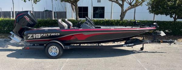 2024 Nitro Z19 fishing boat with trailer, black and red design, parked outdoors.