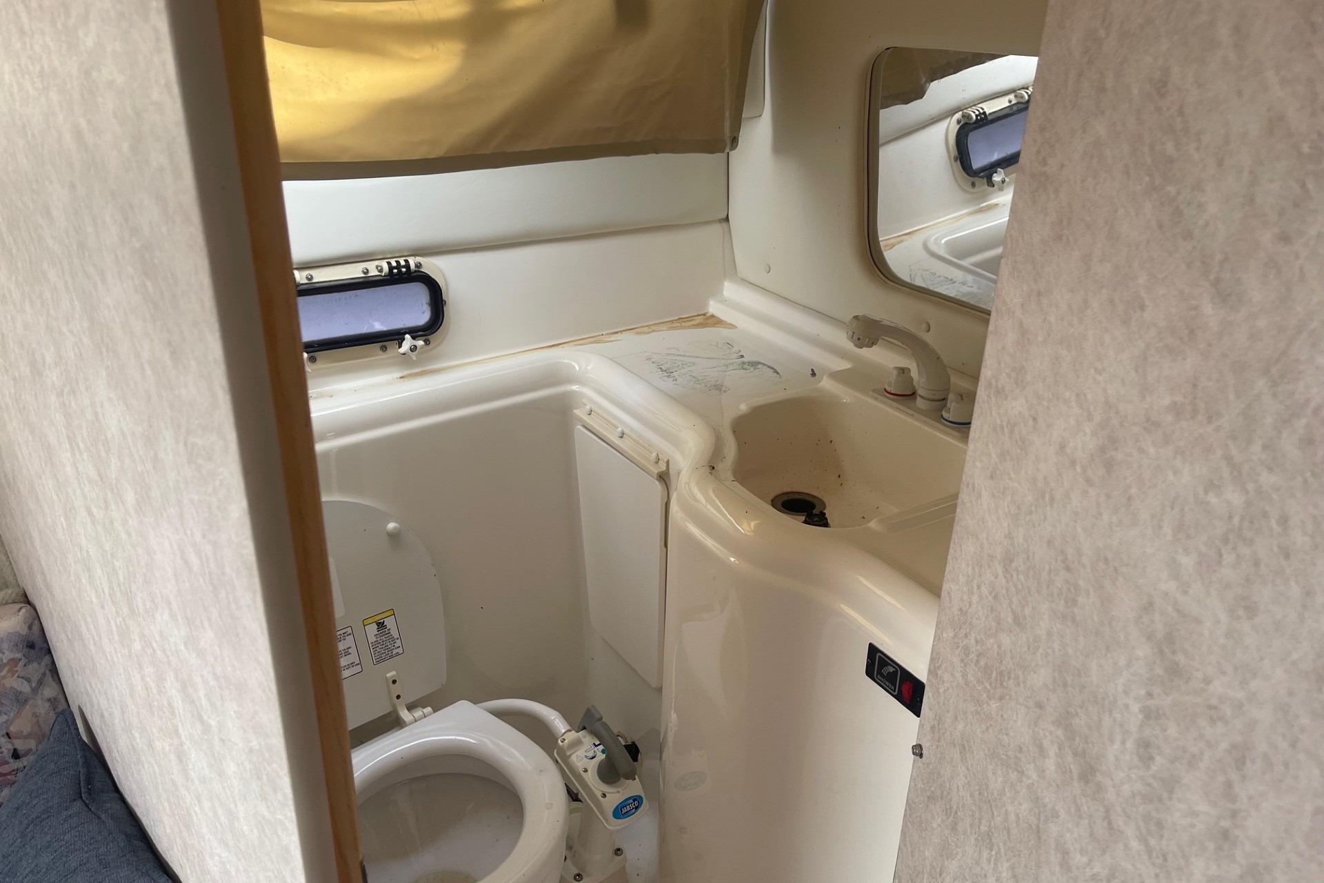1997 Bayliner 2655 Ciera boat bathroom with toilet, sink, and small window.