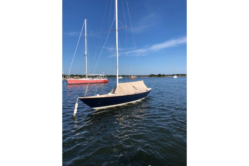 1963 Cape Cod Shipbuilding Shields sailboat moored on calm water under clear blue sky.