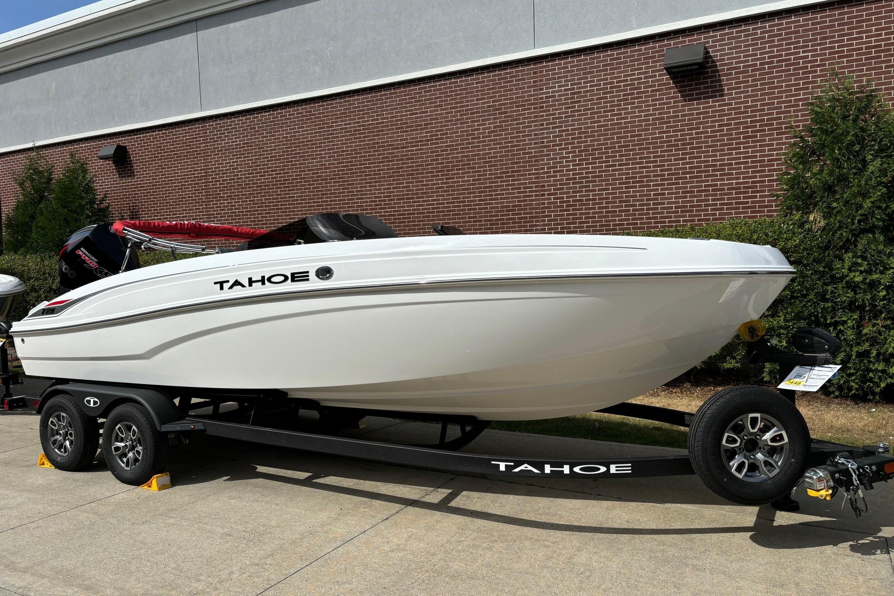 2025 Tahoe T21 boat on trailer, parked outdoors near brick wall.