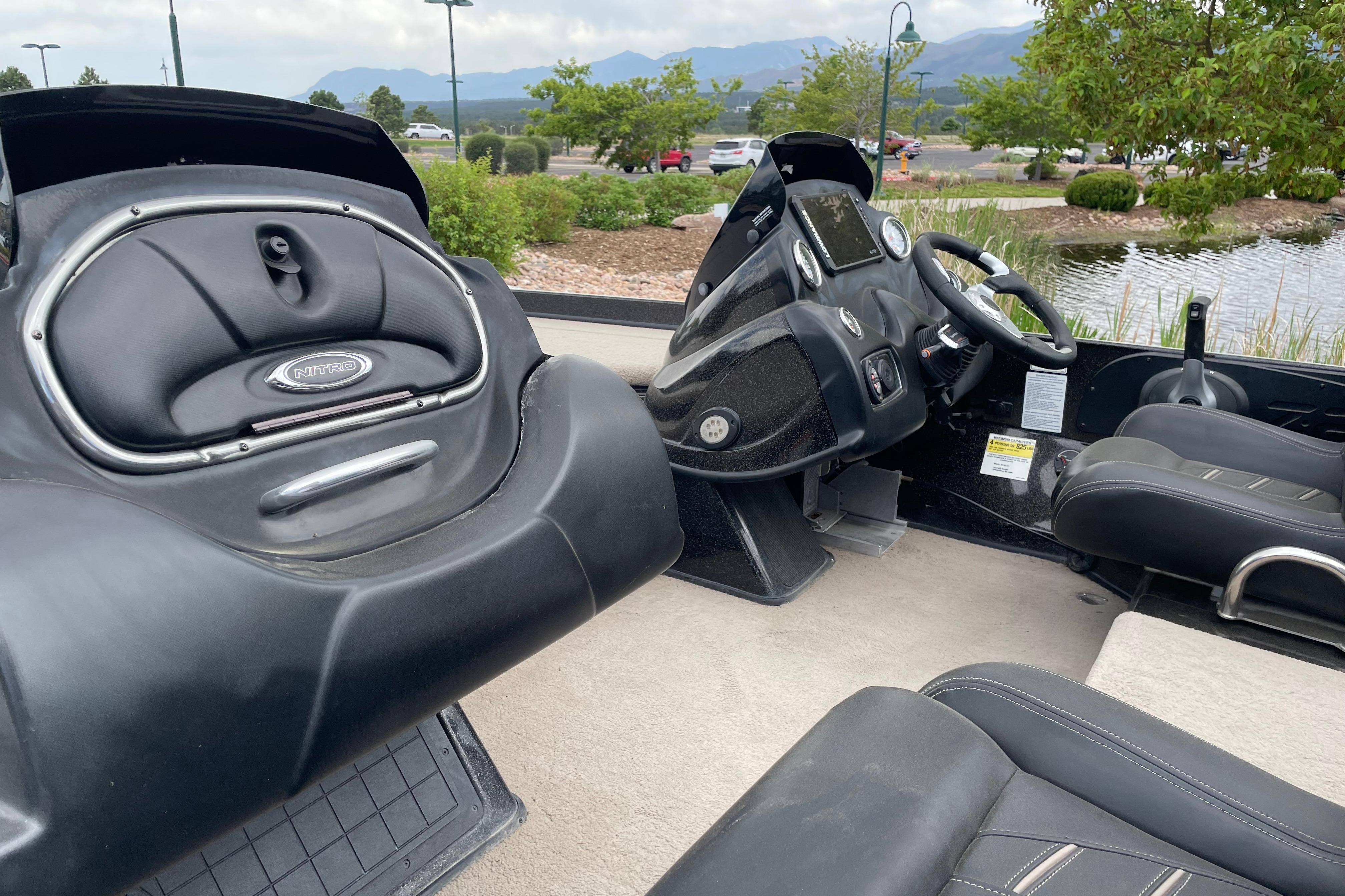 2016 Nitro Z21 boat interior with steering wheel and seating, parked near a pond.