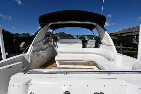 1997 Sea Ray 400 Sundancer yacht with spacious white seating and black canopy under clear blue sky.