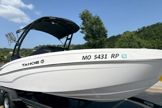 2024 Tahoe T21 boat on trailer, white hull, black canopy, parked outdoors.