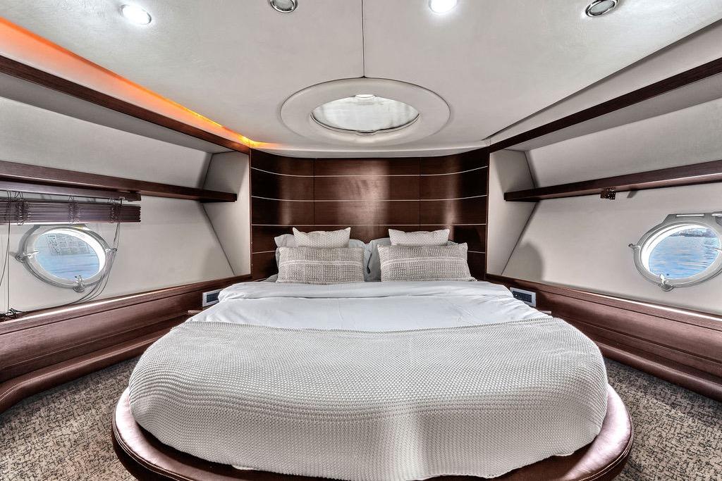 Luxurious bedroom interior of 2006 Azimut 68S yacht with elegant design and porthole windows.