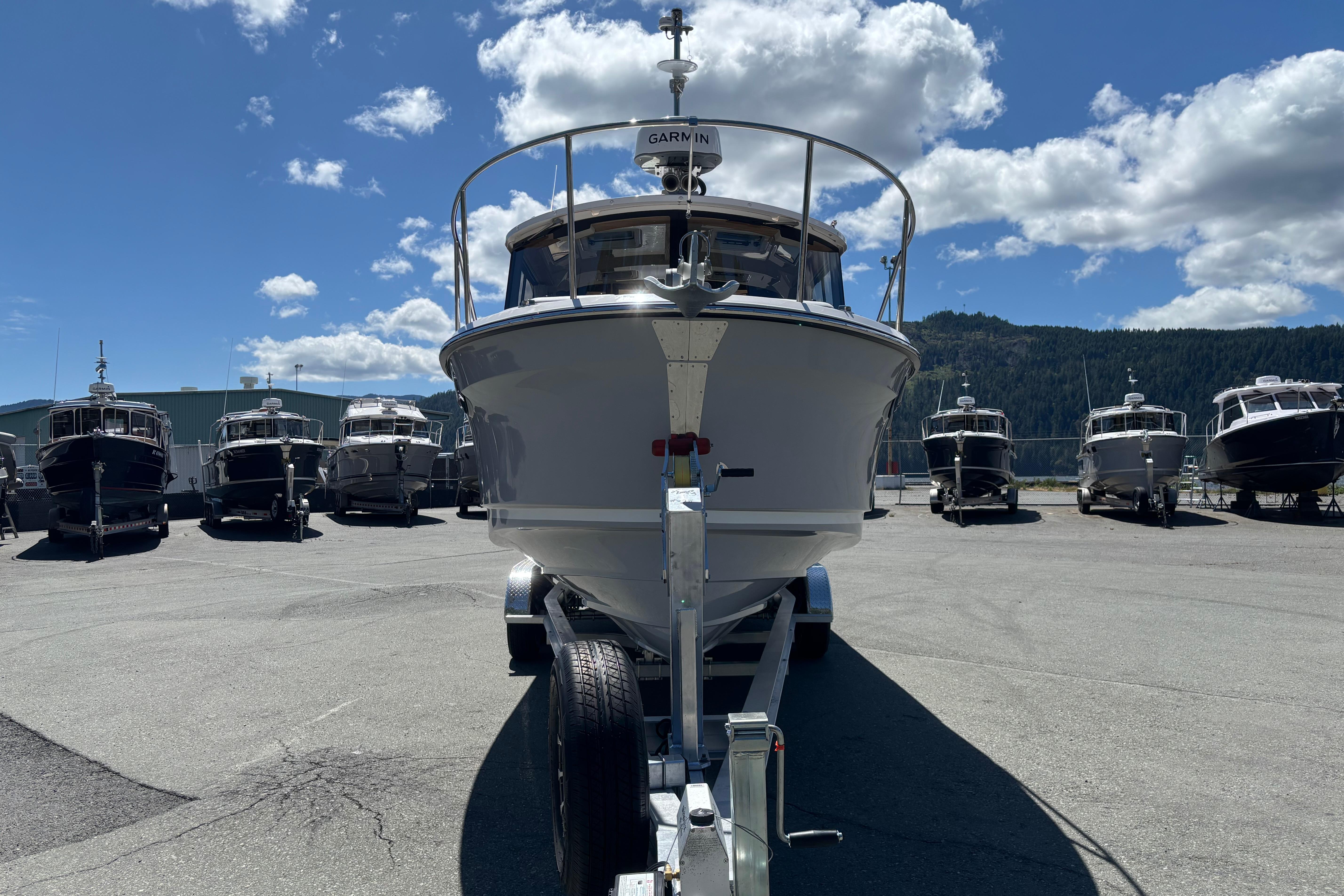 2026 Ranger Tugs R-25 boat on trailer, surrounded by other boats, under a blue sky.