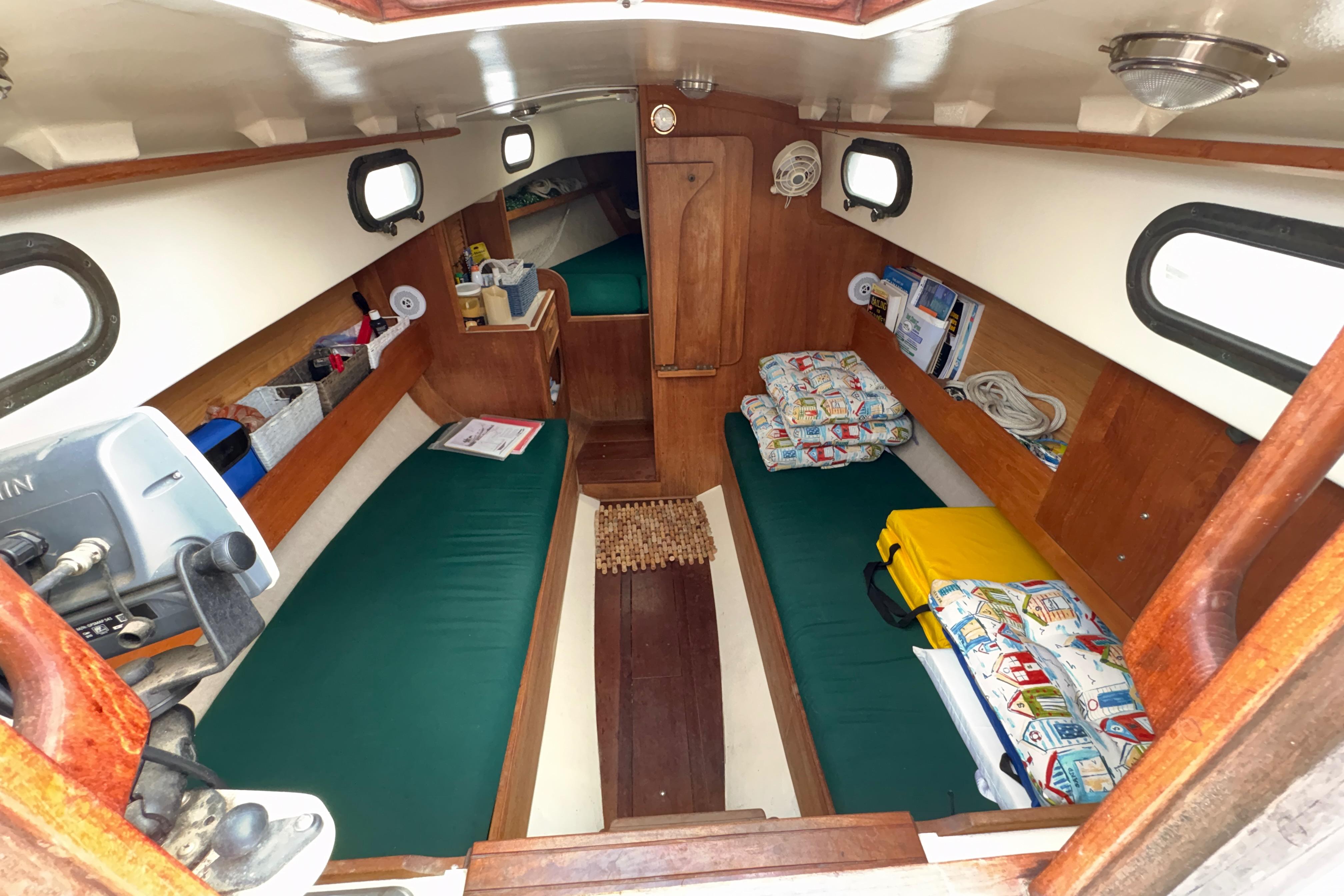 Interior of 1986 Cape Dory 26 sailboat with green cushions and wooden accents.
