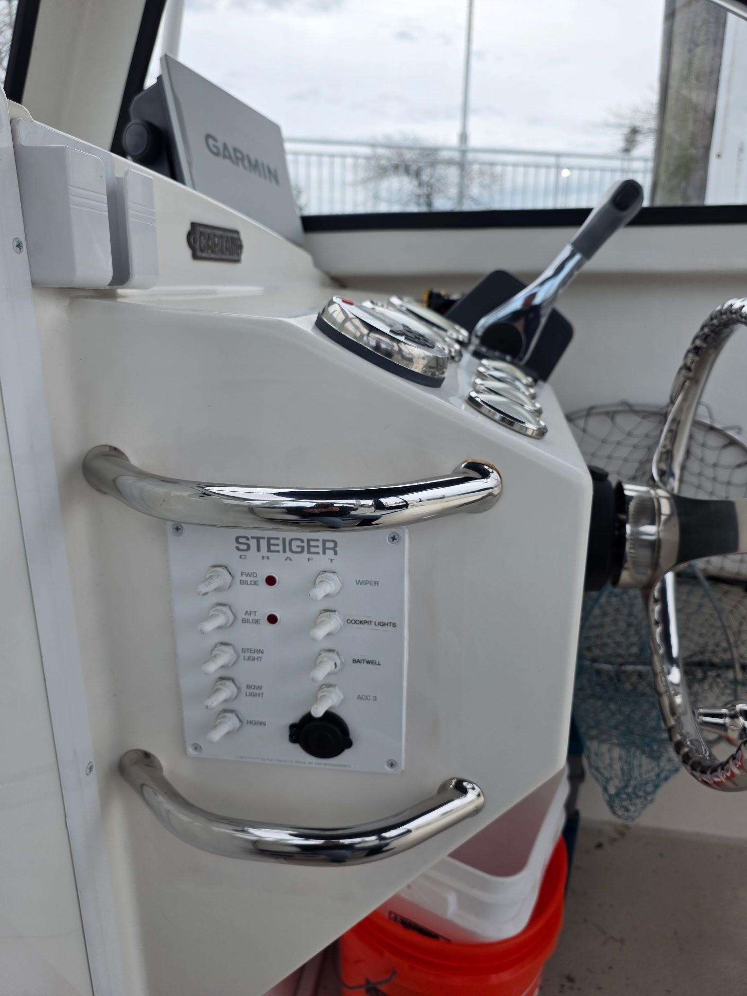 Close-up of a boat's helm with steering wheel and control panel.