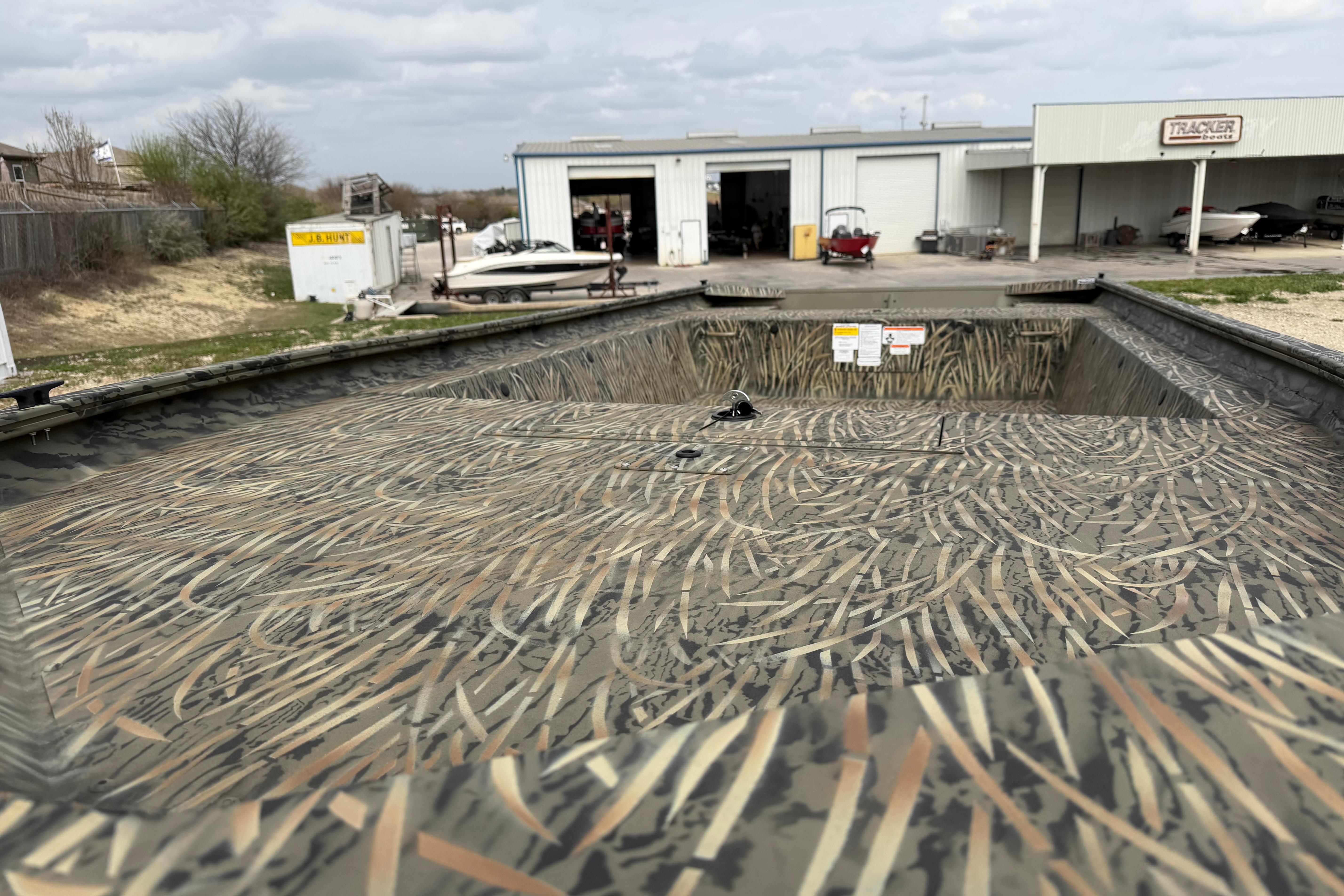2026 Tracker Grizzly 1754 Utility boat with camouflage design at a service facility.