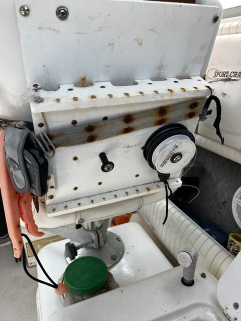 Close-up of a boat part with rusty screws and fishing gear. "Sport-Craft" is visible.