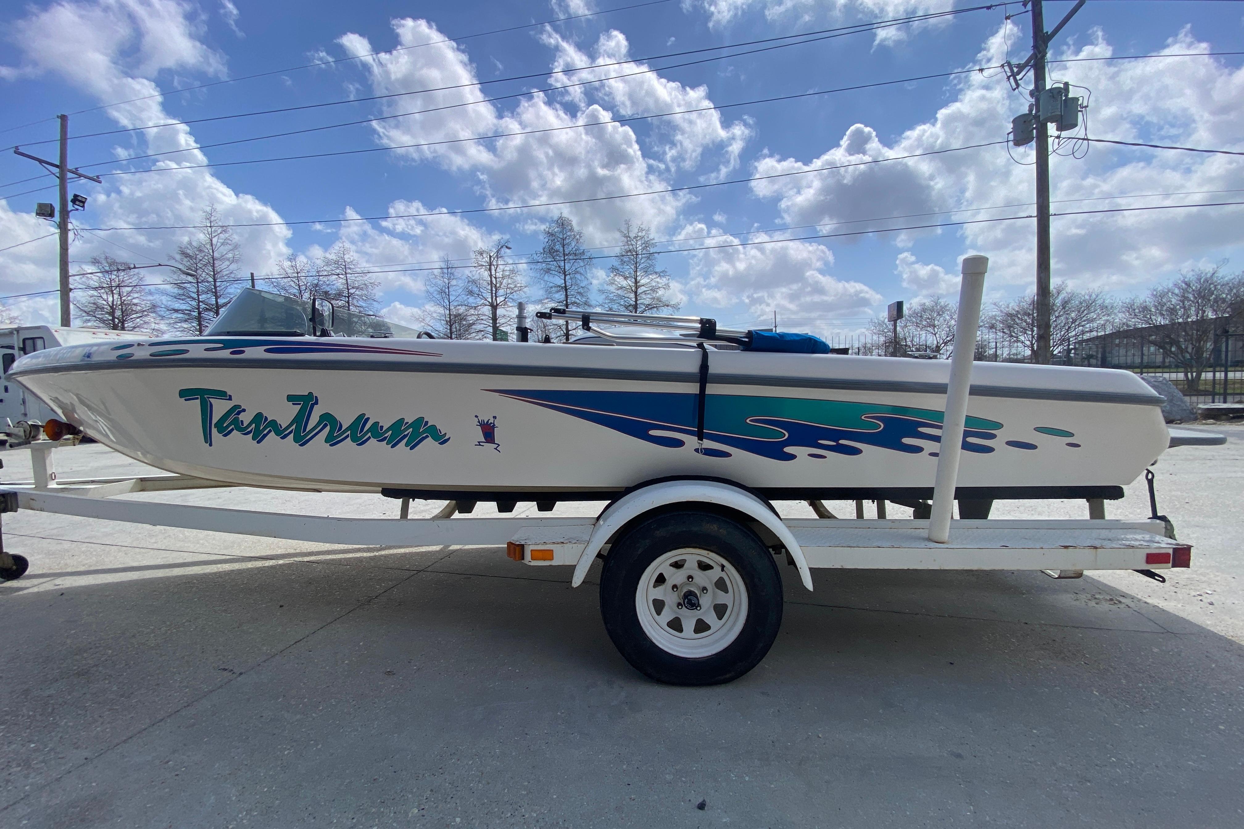 1997 Malibu Tantrum boat on trailer under a bright blue sky.