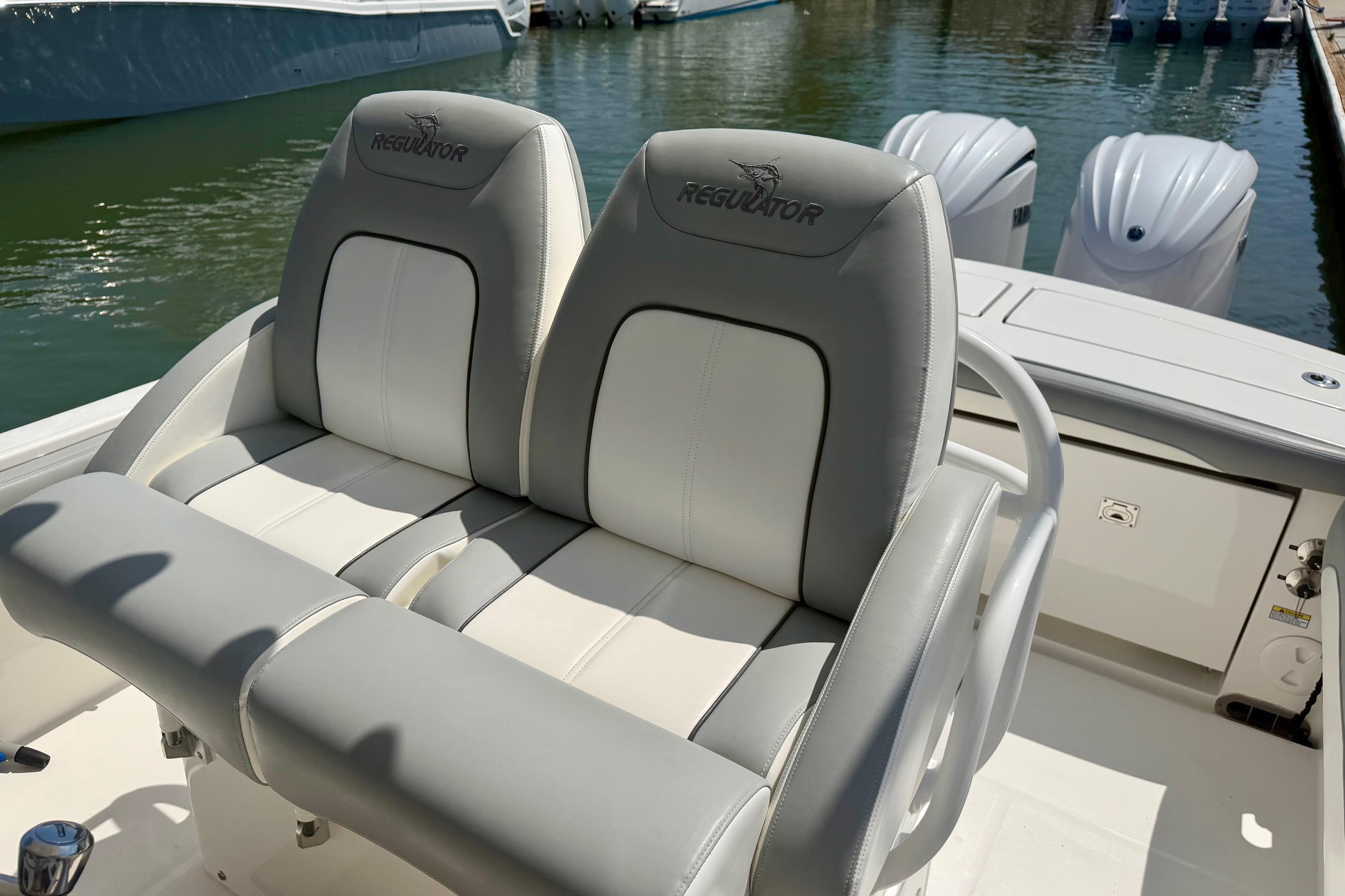 2022 Regulator 28 boat with dual cushioned seats and twin engines at dock.