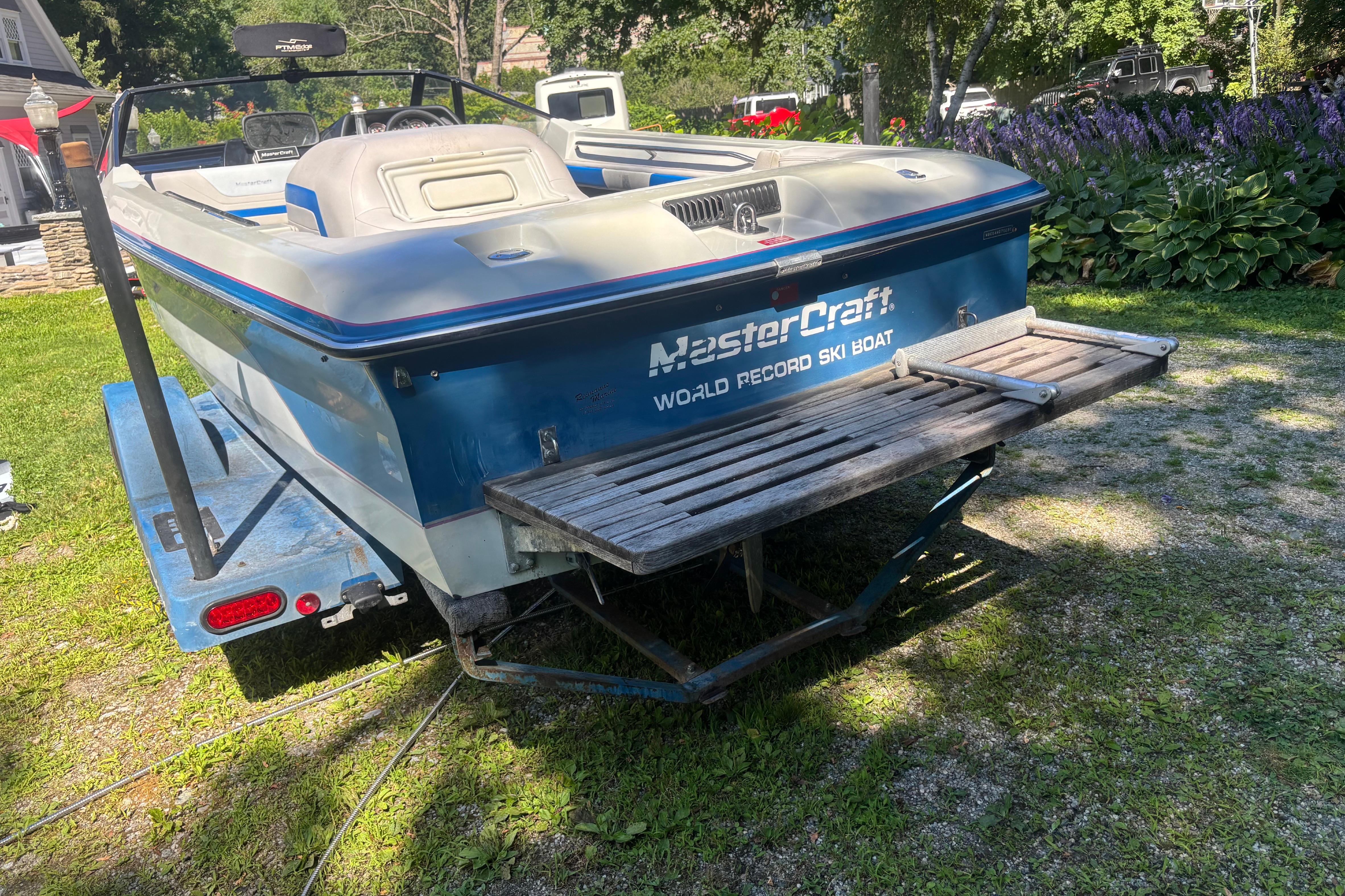 1990 MasterCraft ProStar 190 ski boat on trailer, parked on grass.