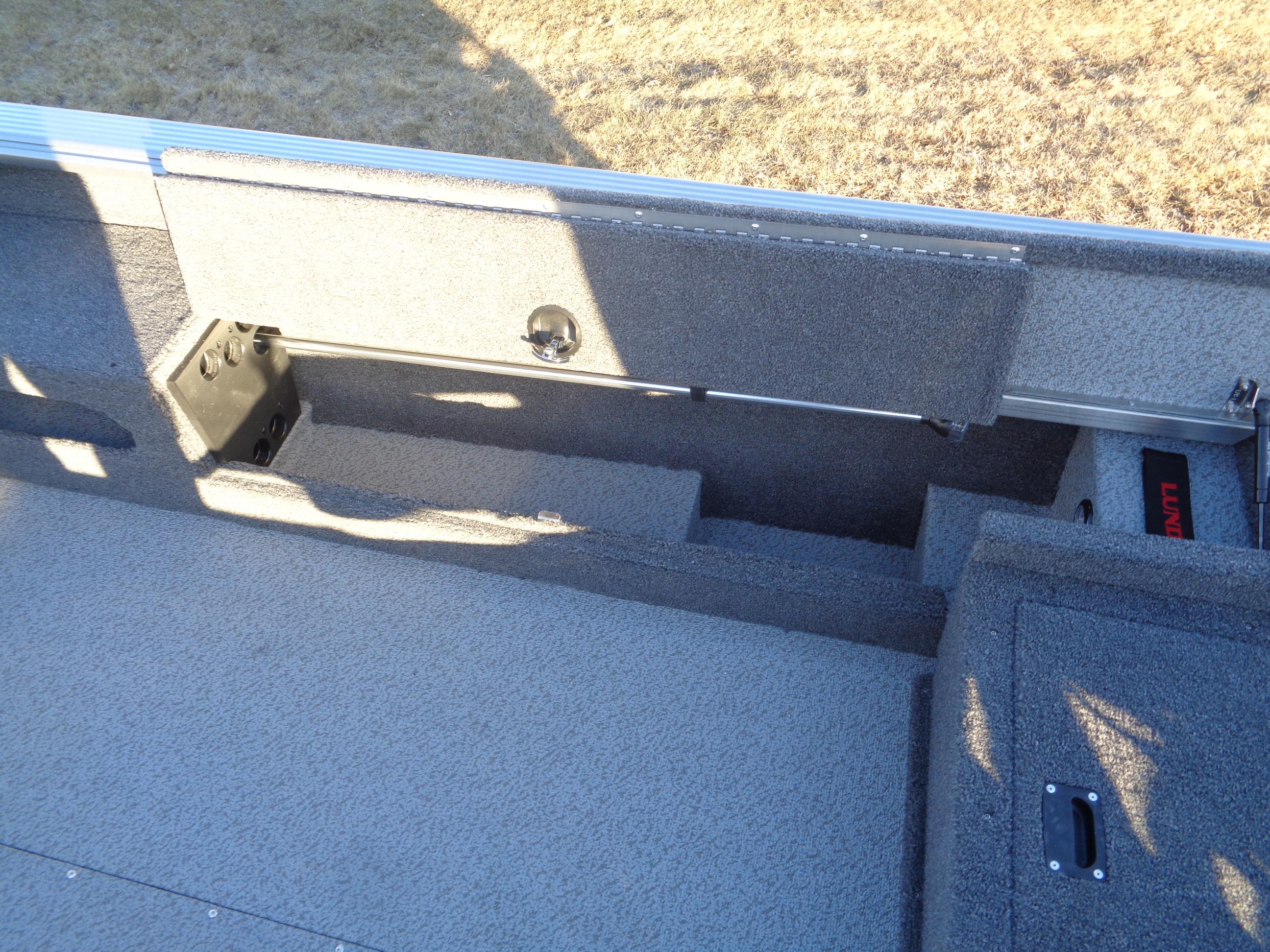 2025 Lund 1875 Pro Guide boat interior with storage compartments and carpeted flooring.