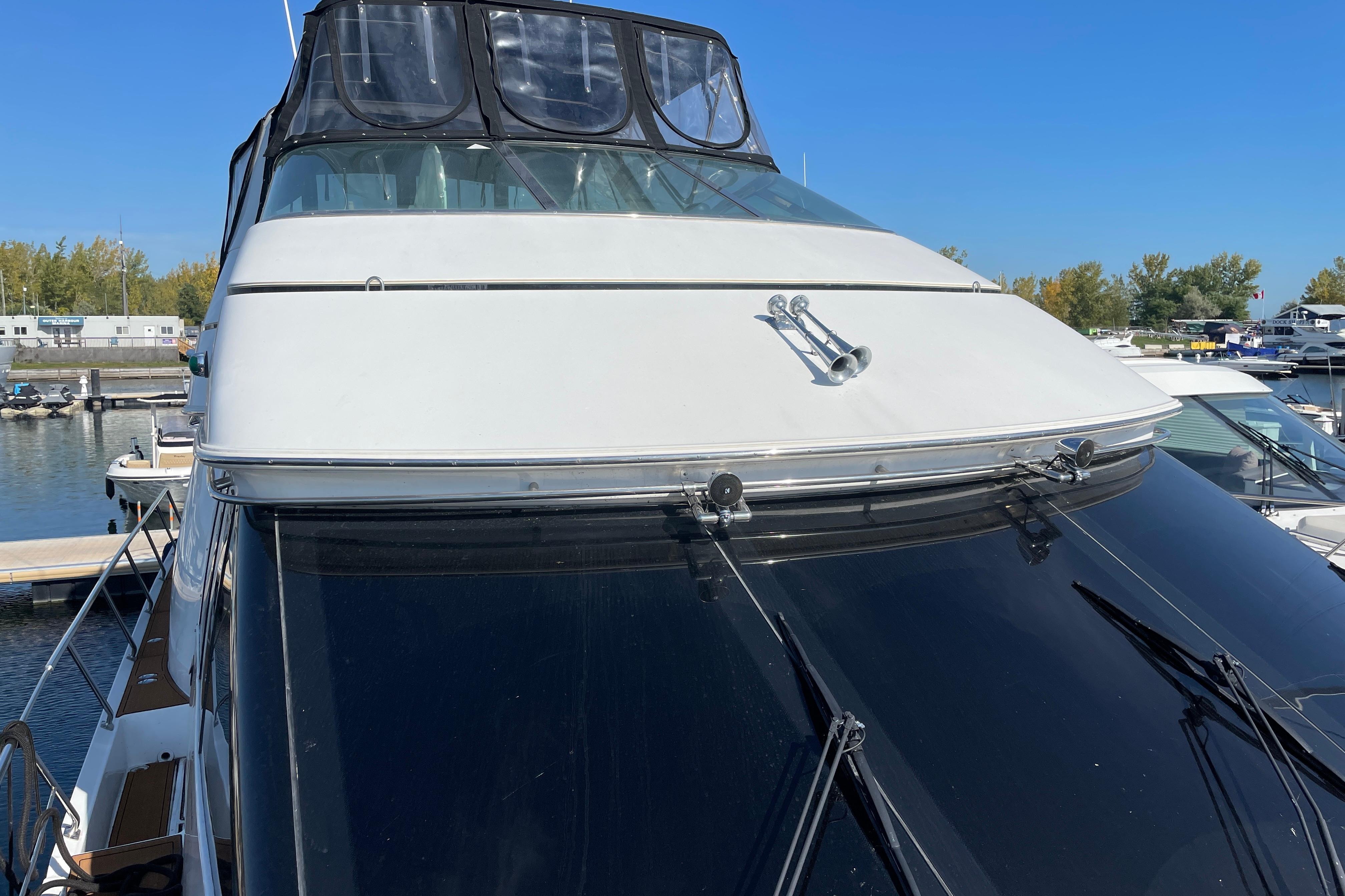 2002 Carver 570 Voyager Pilothouse yacht docked at marina under clear blue sky.