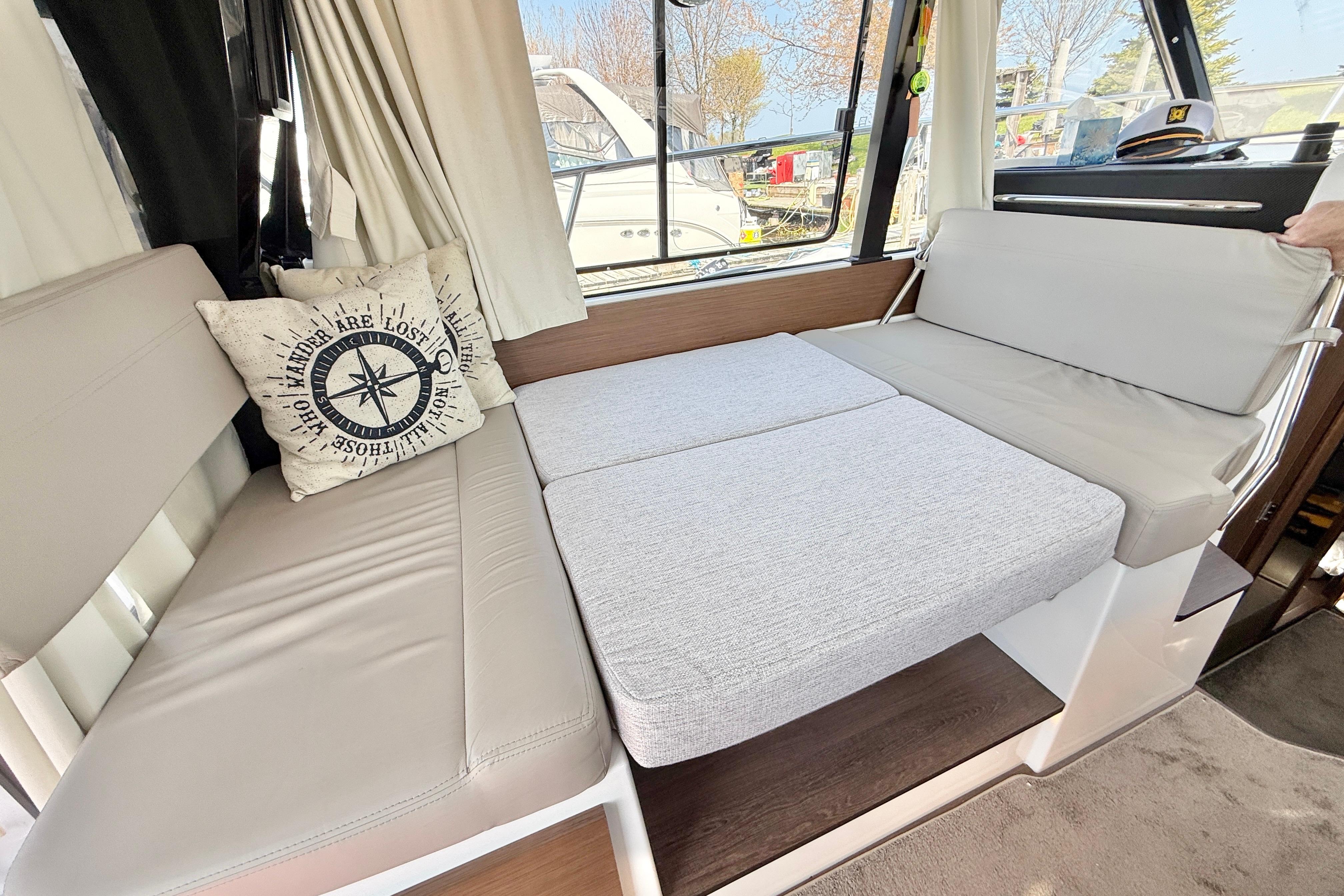 Interior of 2022 Jeanneau NC 1095 Fly with convertible seating and nautical-themed pillow.