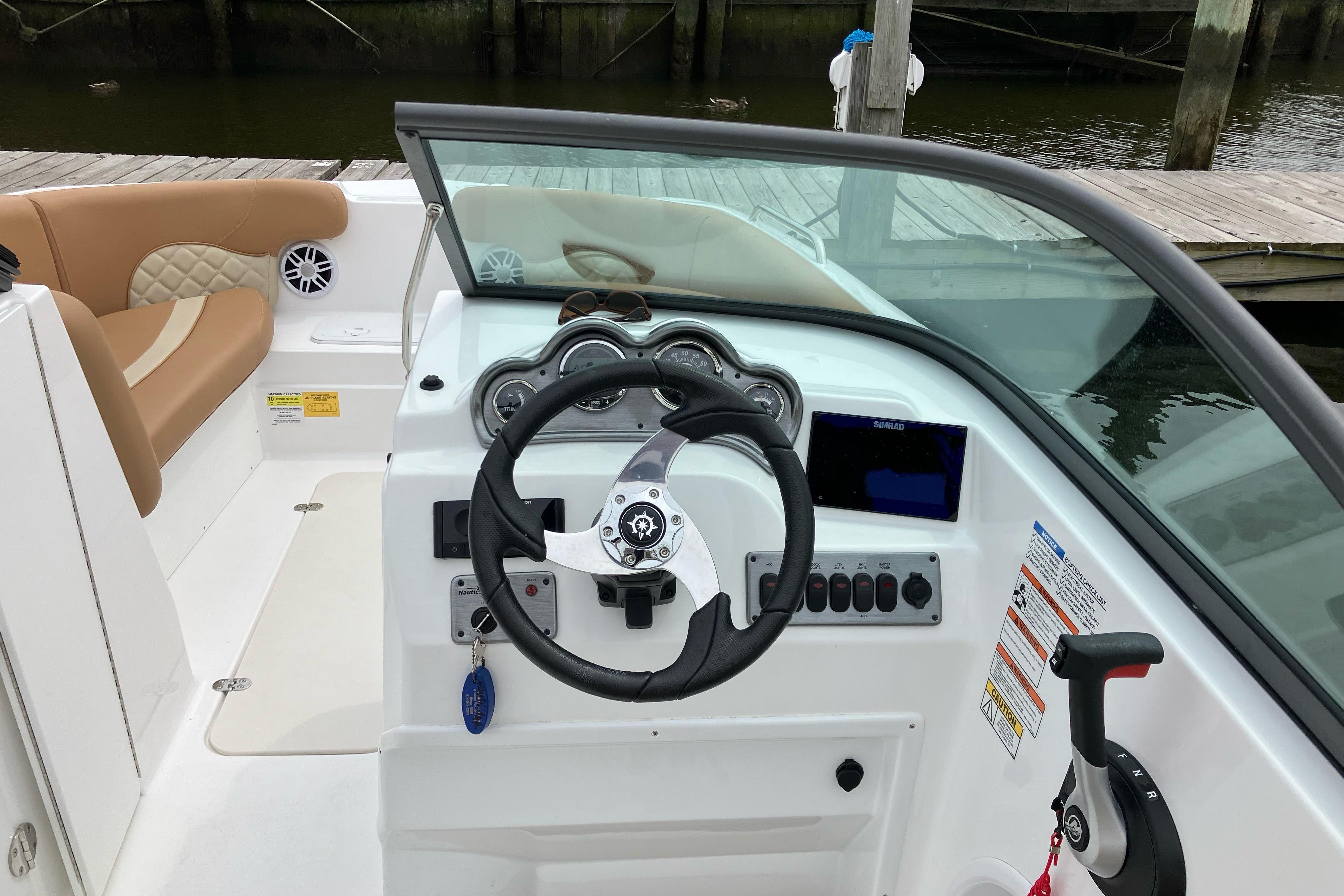 2025 NauticStar 223 DC Deck boat interior with steering wheel and dashboard controls.