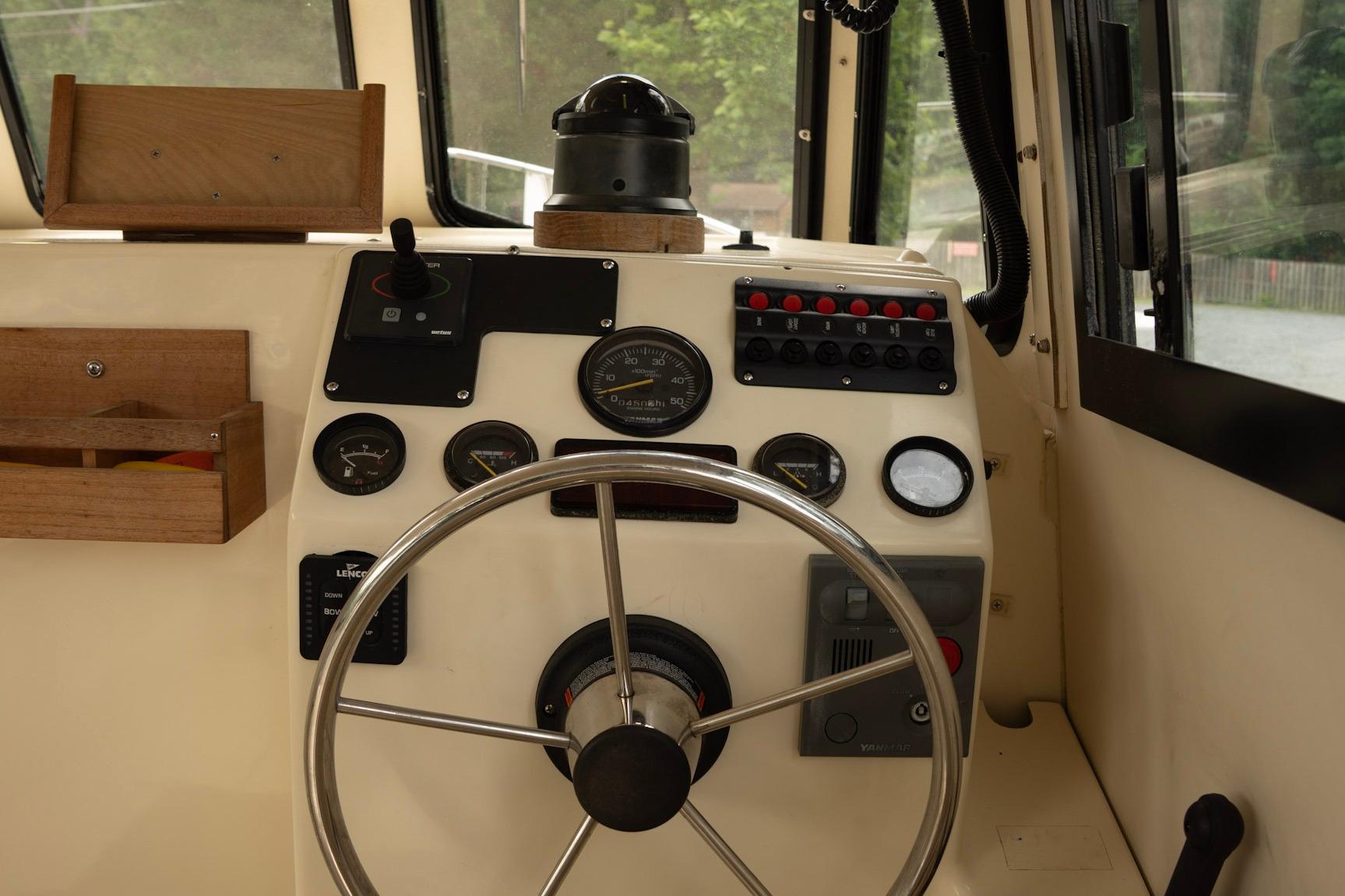 Interior helm of 2006 Atlas Boat Works Acadia 25 with steering wheel and control panel.