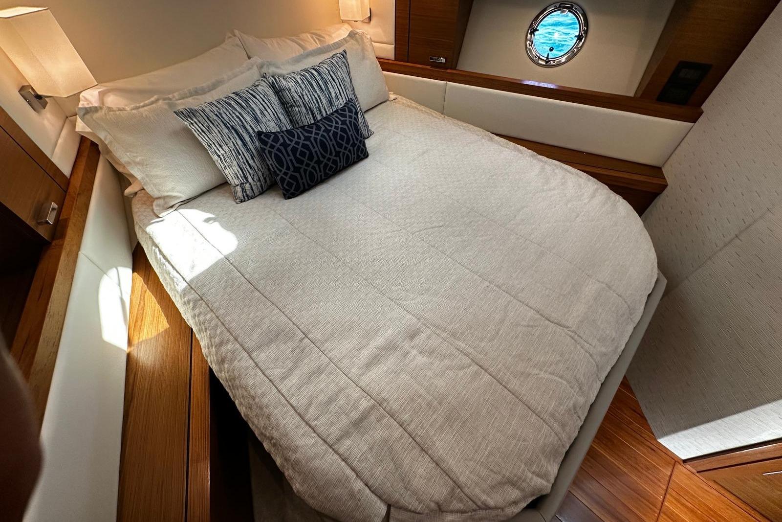 Luxurious bedroom interior of 2022 Tiara Yachts C39 Coupe with elegant bedding and porthole view.