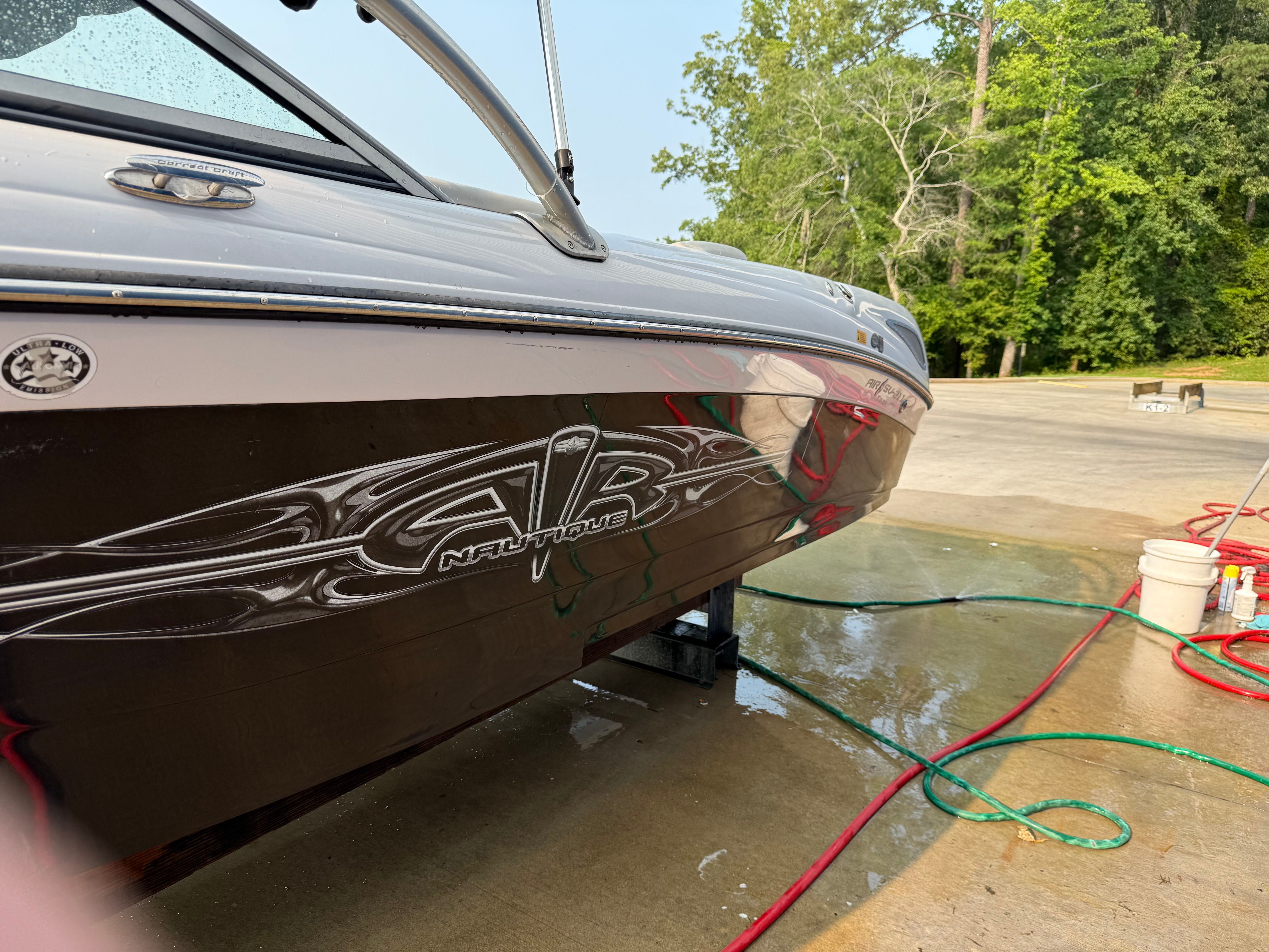 A 2007 Nautique SV 211 boat on wet concrete. Hoses and buckets are visible nearby.