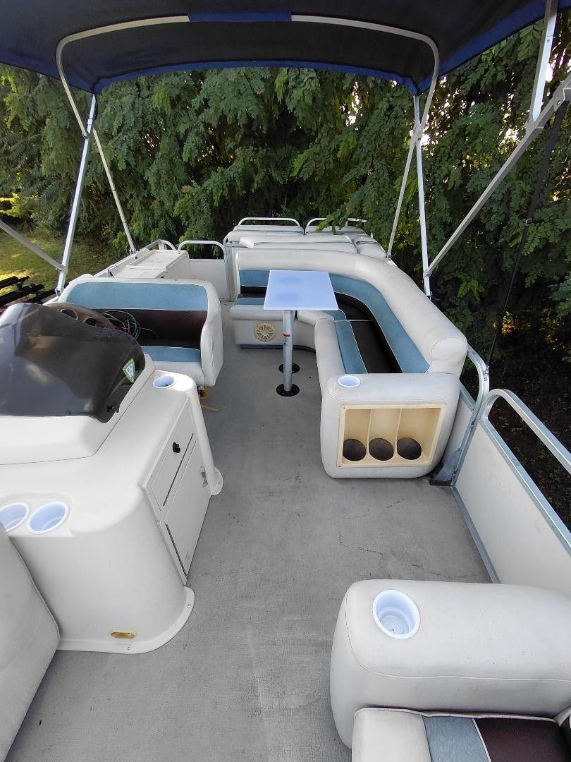 The image shows the deck of a 1999 Premier 250 Grand Majestic pontoon boat with seating and a table.