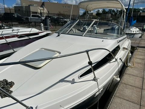 A 1997 Bayliner 2566 Ciera docked. It features a white canopy and sleek lines.