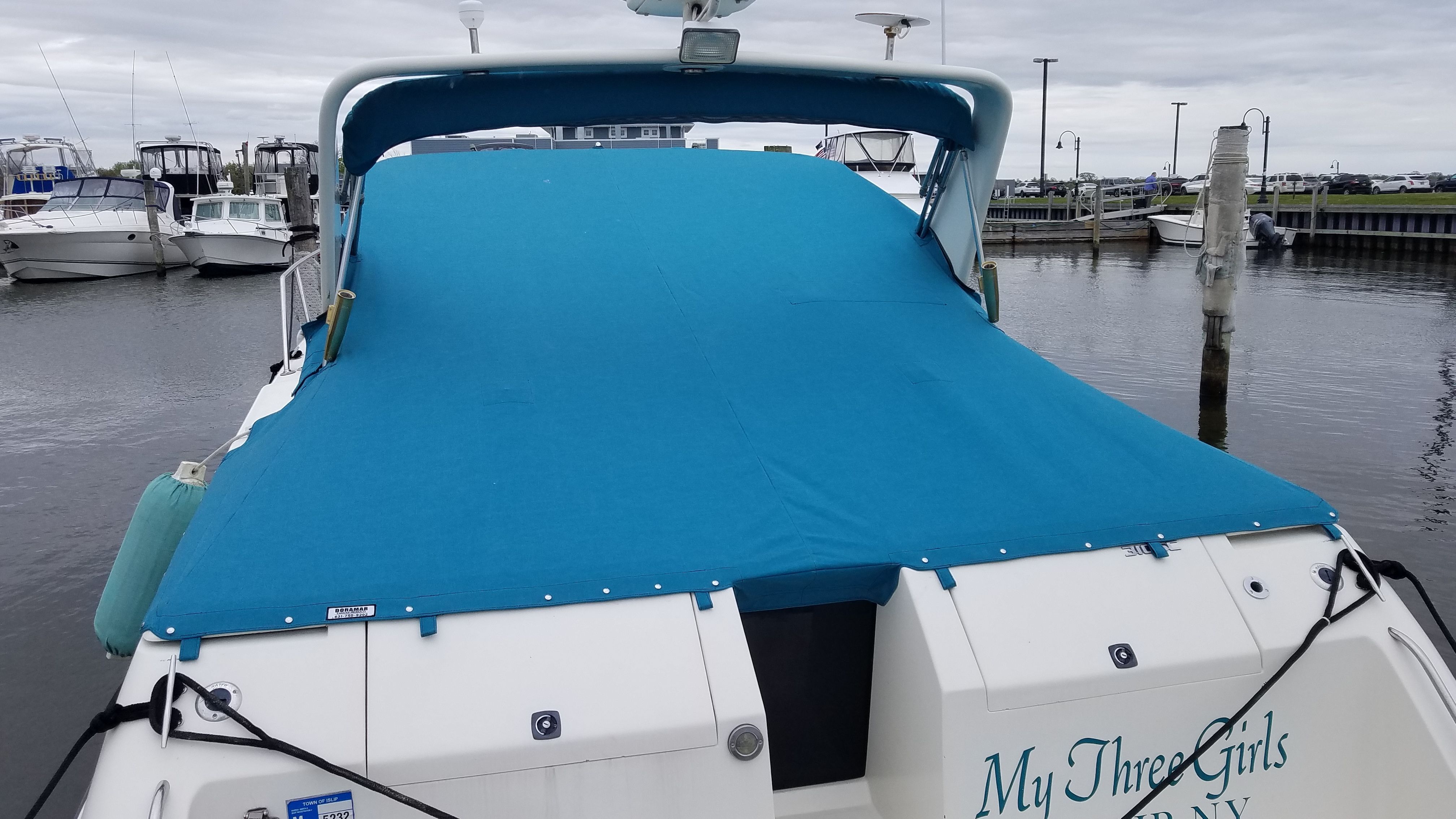 A 1989 Tiara Yachts Slickcraft with a blue cover docked in a marina.