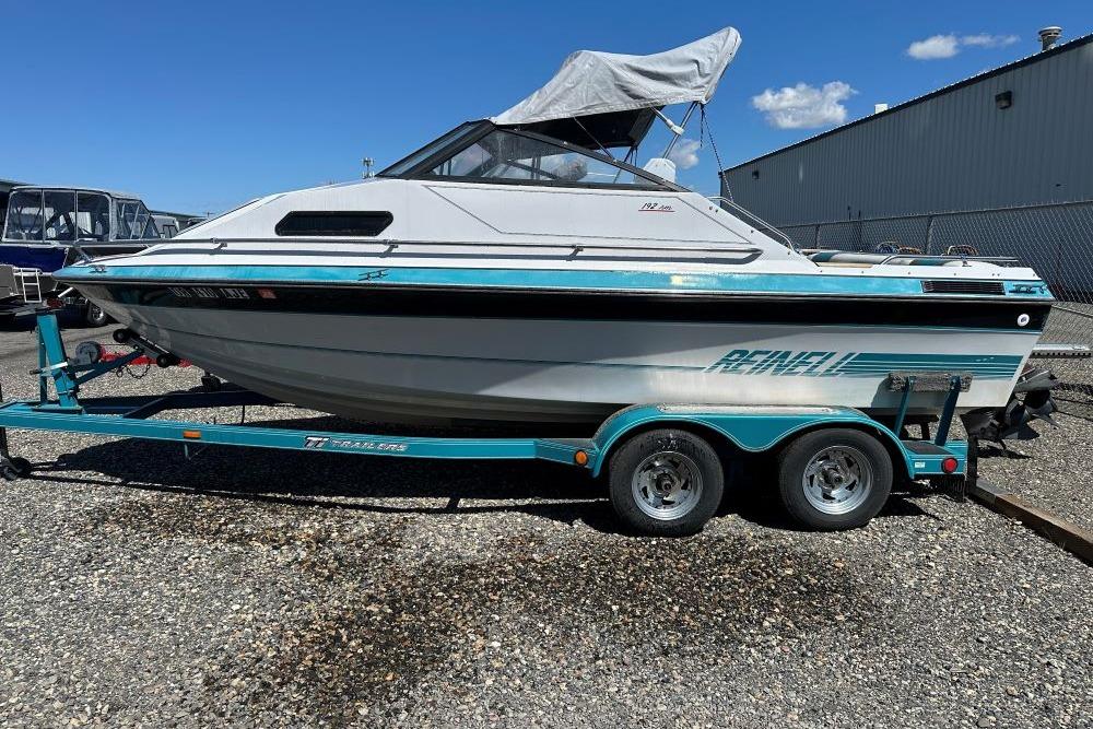 1992 Reinell 192 RM boat on trailer, parked outdoors under clear blue sky.