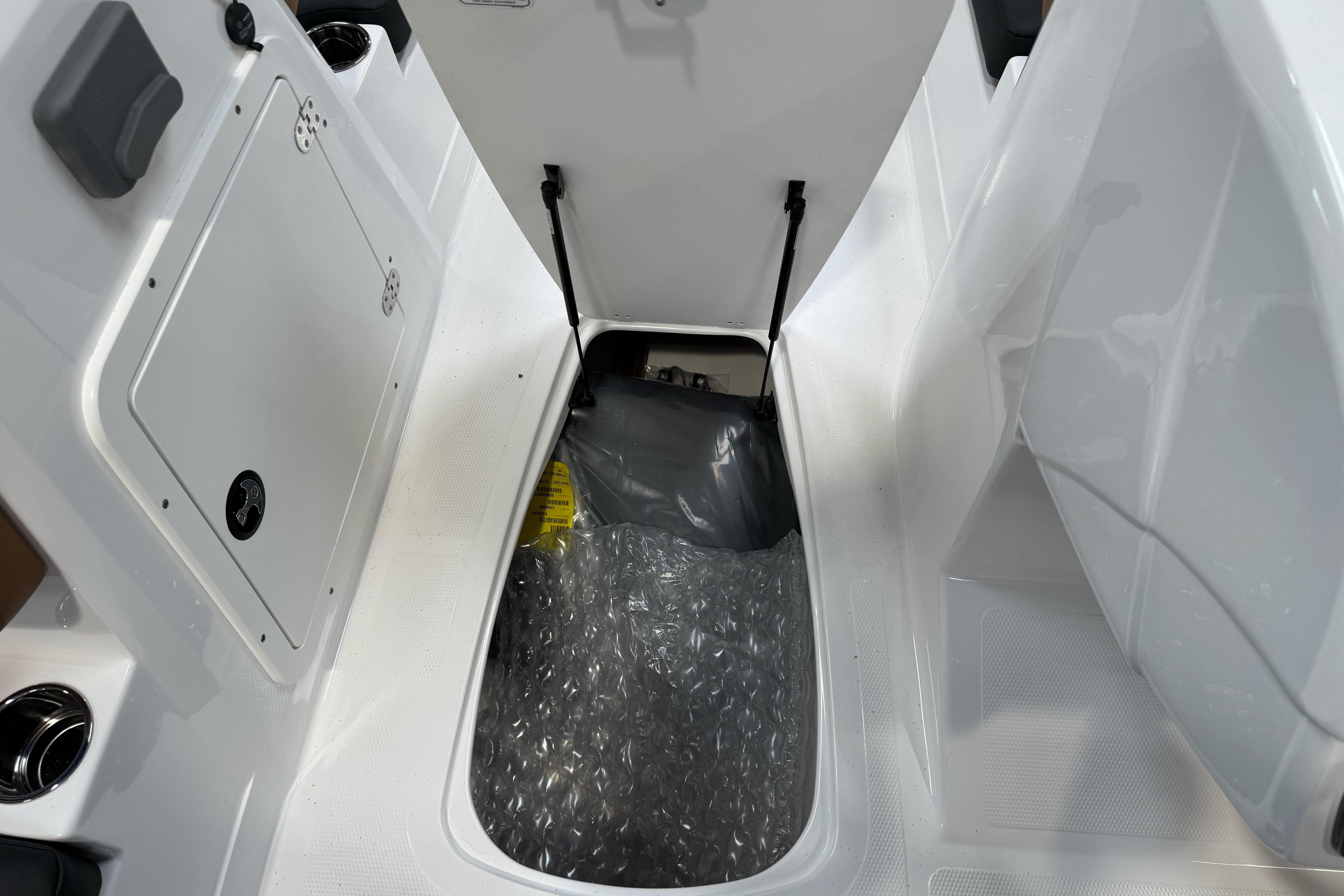 Open storage compartment in 2026 Tahoe 2150 boat, featuring bubble wrap and secure latch.