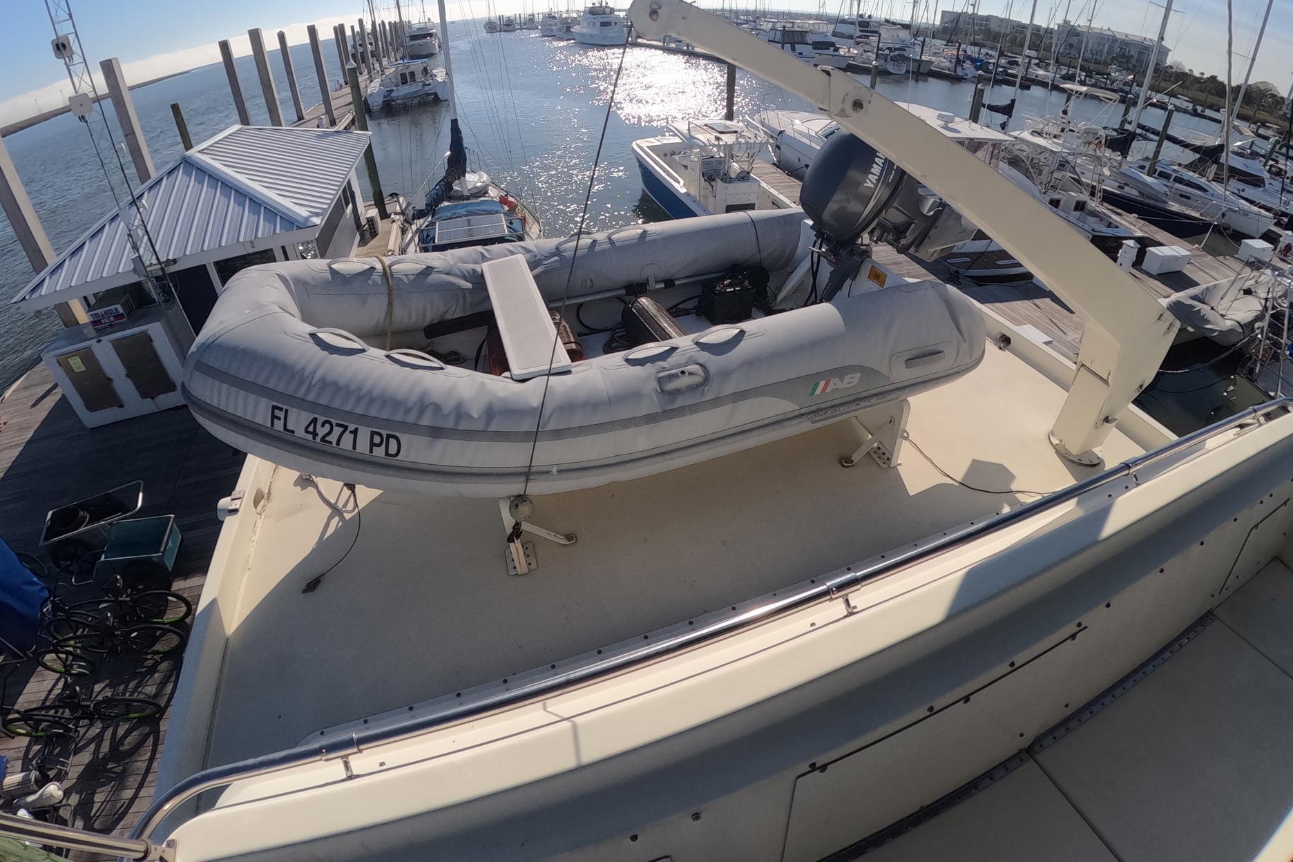 1987 Hatteras 54 Motor Yacht with inflatable dinghy on deck at marina.