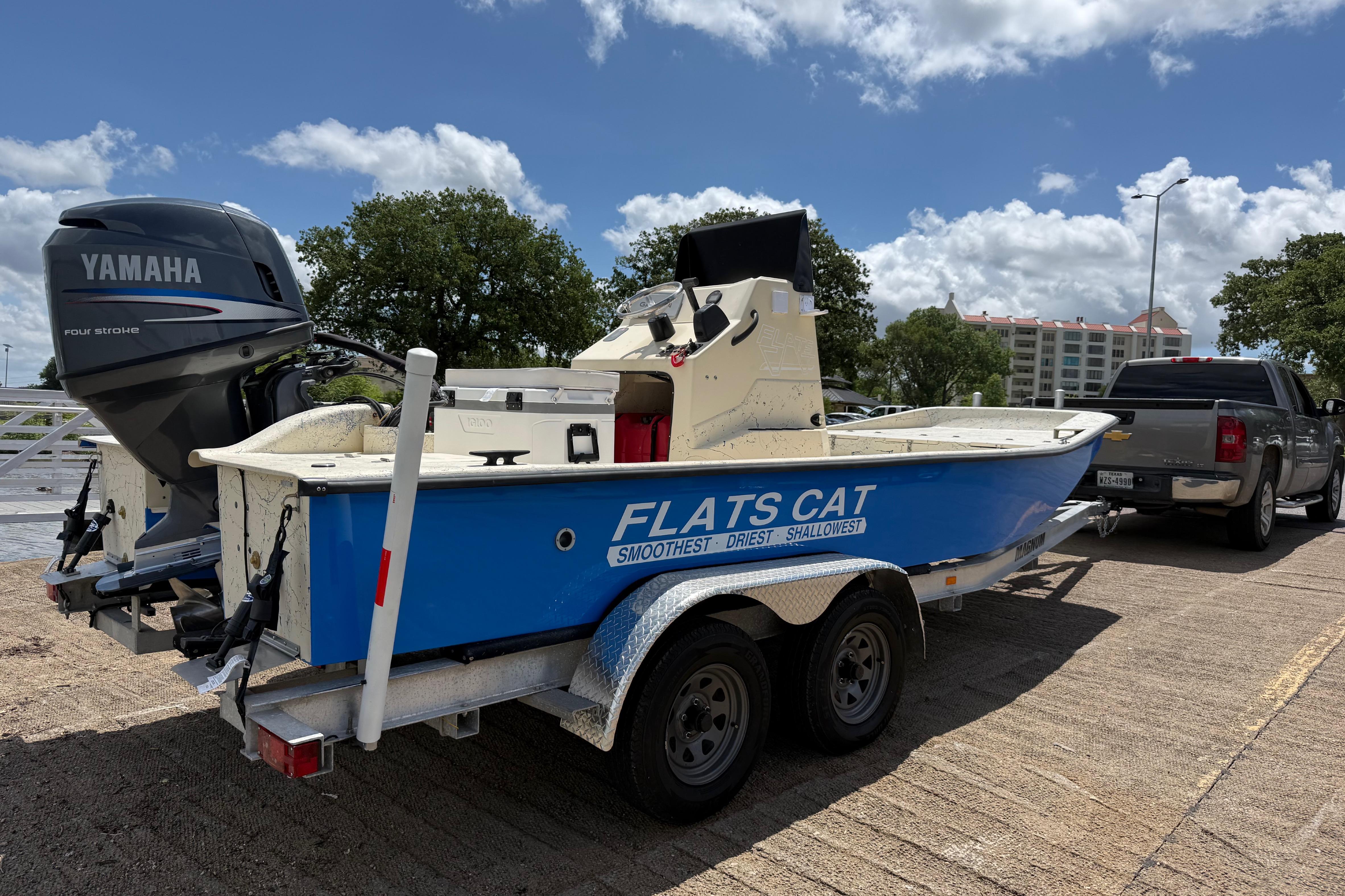 Blue 2007 Flats Cat 19 boat on trailer, featuring Yamaha outboard motor, parked outdoors.