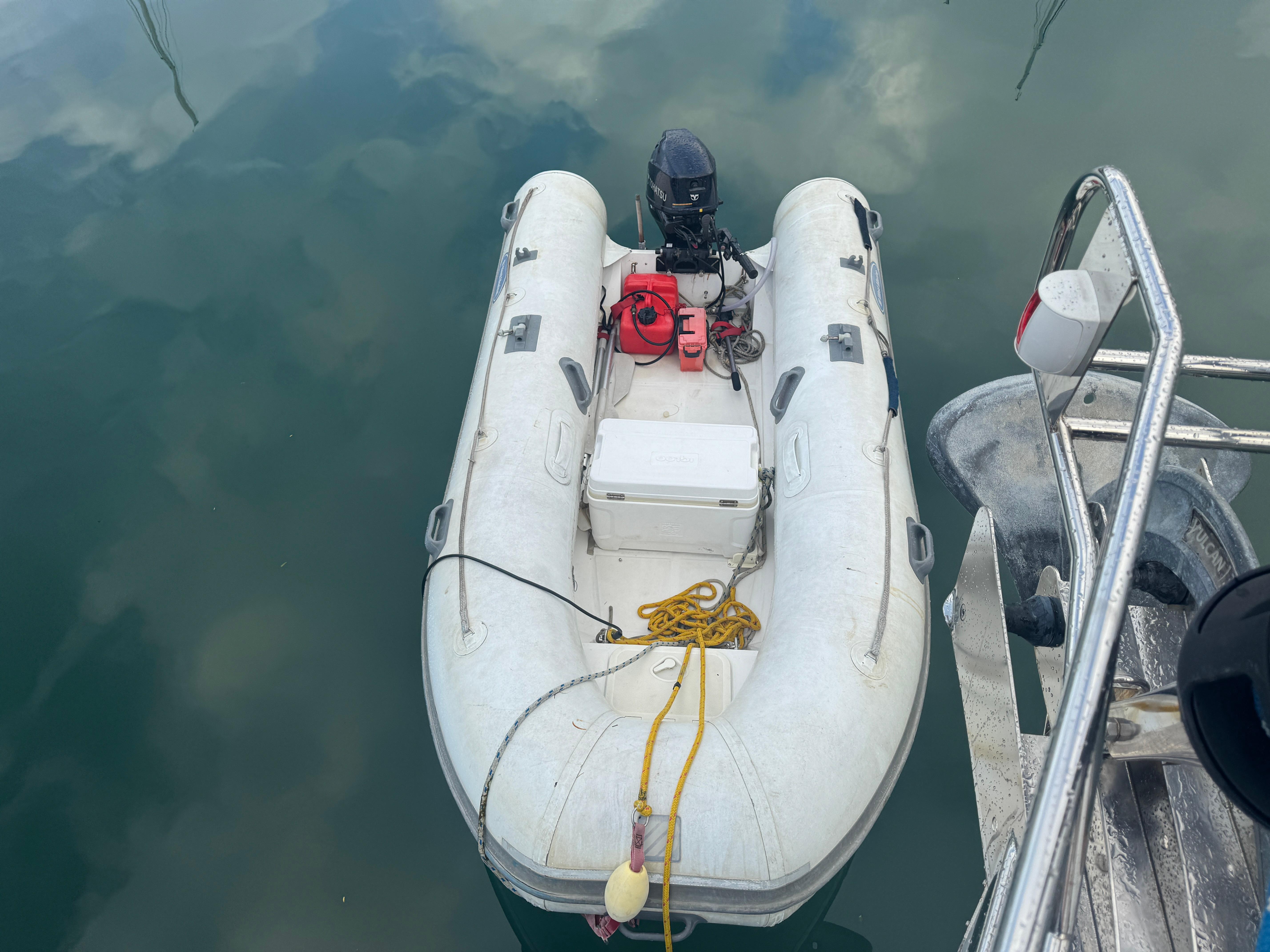 Inflatable dinghy tied to a Beneteau 523 Oceanis, 2005 model, floating on calm water.