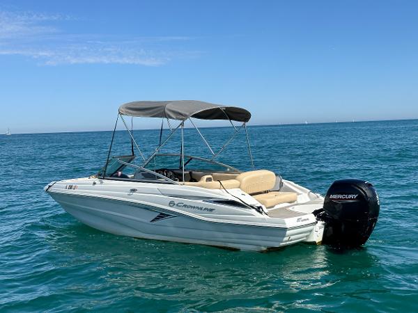 2023 Crownline 215 XS boat on clear blue water with Mercury outboard motor.