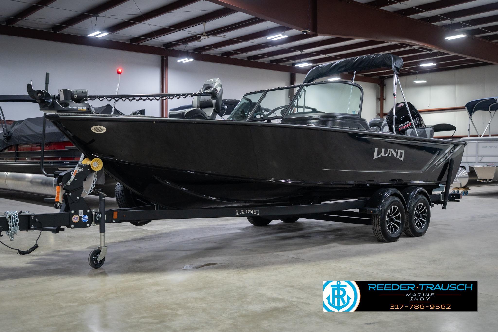 2026 Lund 2075 Impact XS boat in showroom, black exterior, on trailer.