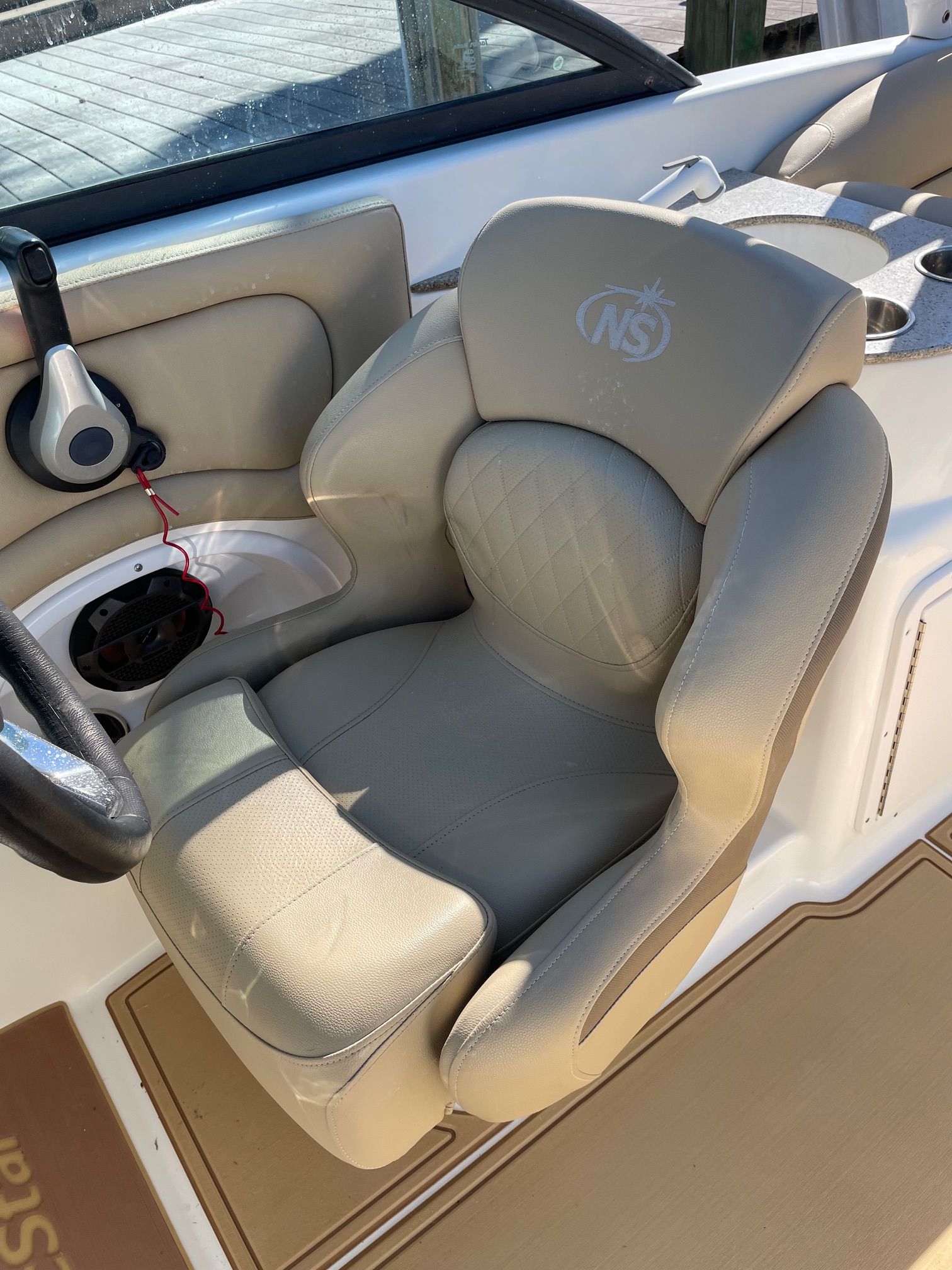 Beige captain's chair with quilted pattern and armrests on a boat.