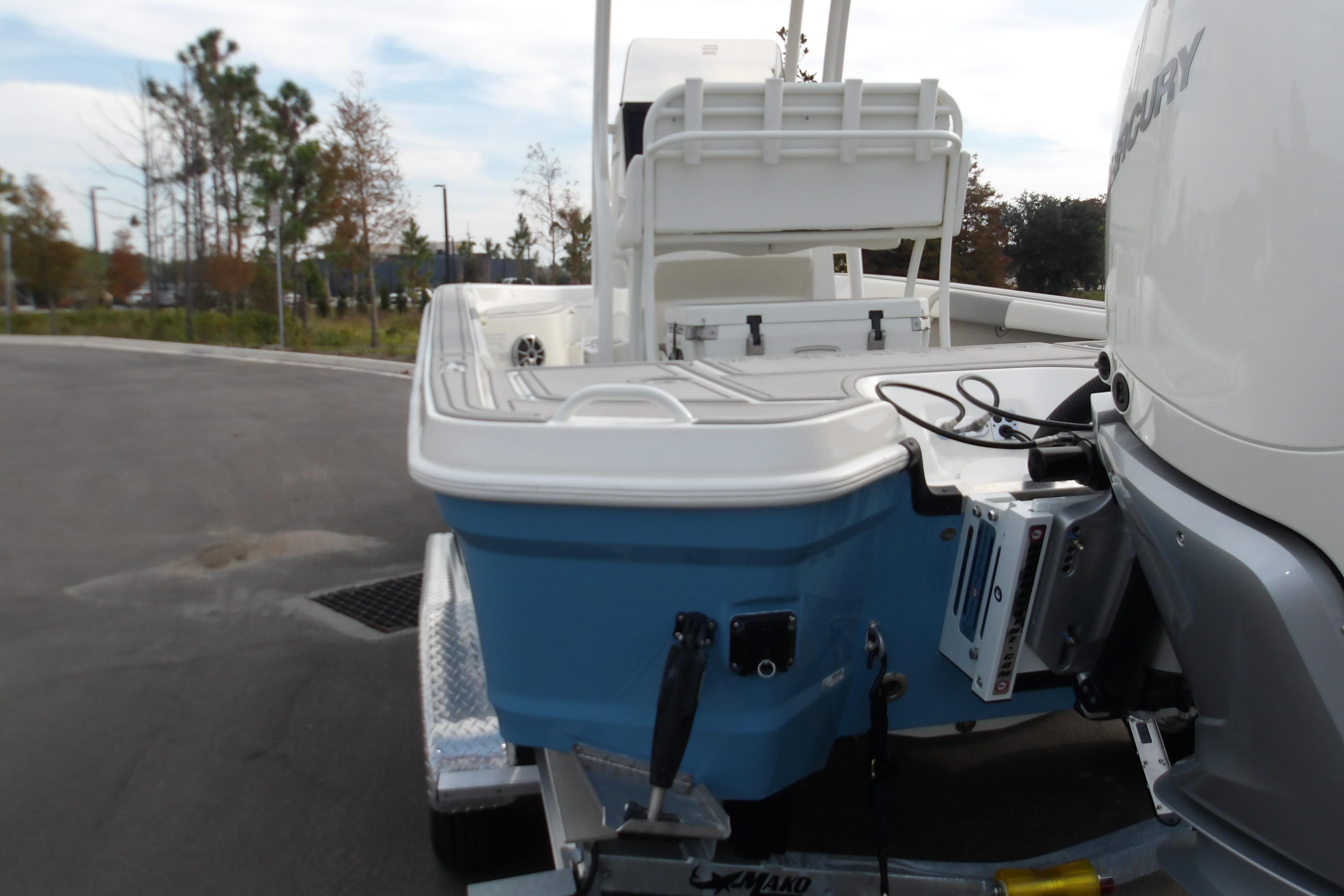 2026 Mako 24 APEX boat on trailer, featuring blue hull and Mercury engine.