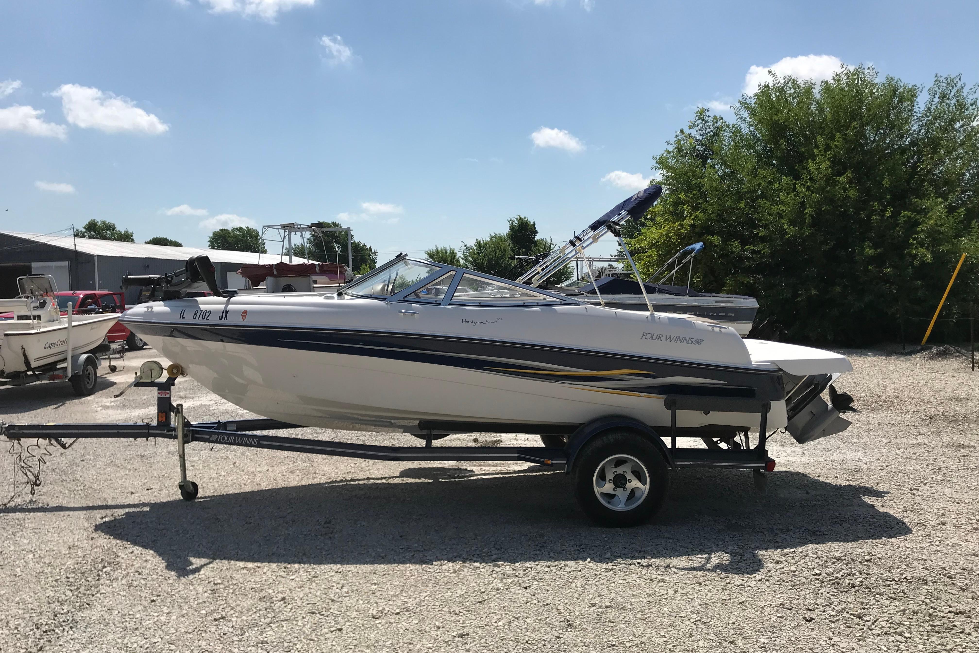 2005 Four Winns 180 Horizon FS boat on trailer, parked outdoors under a clear sky.