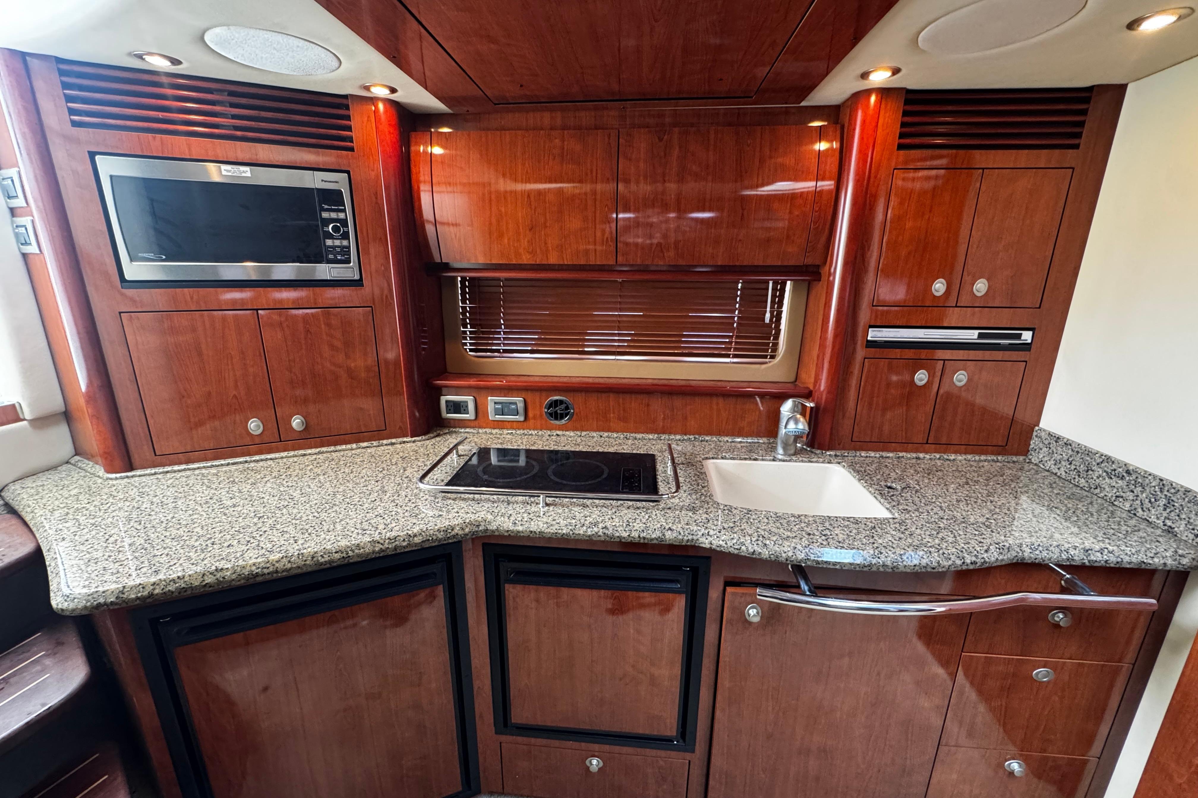 Luxurious 2006 Sea Ray 40 Sundancer yacht kitchen with wood cabinetry and granite countertops.