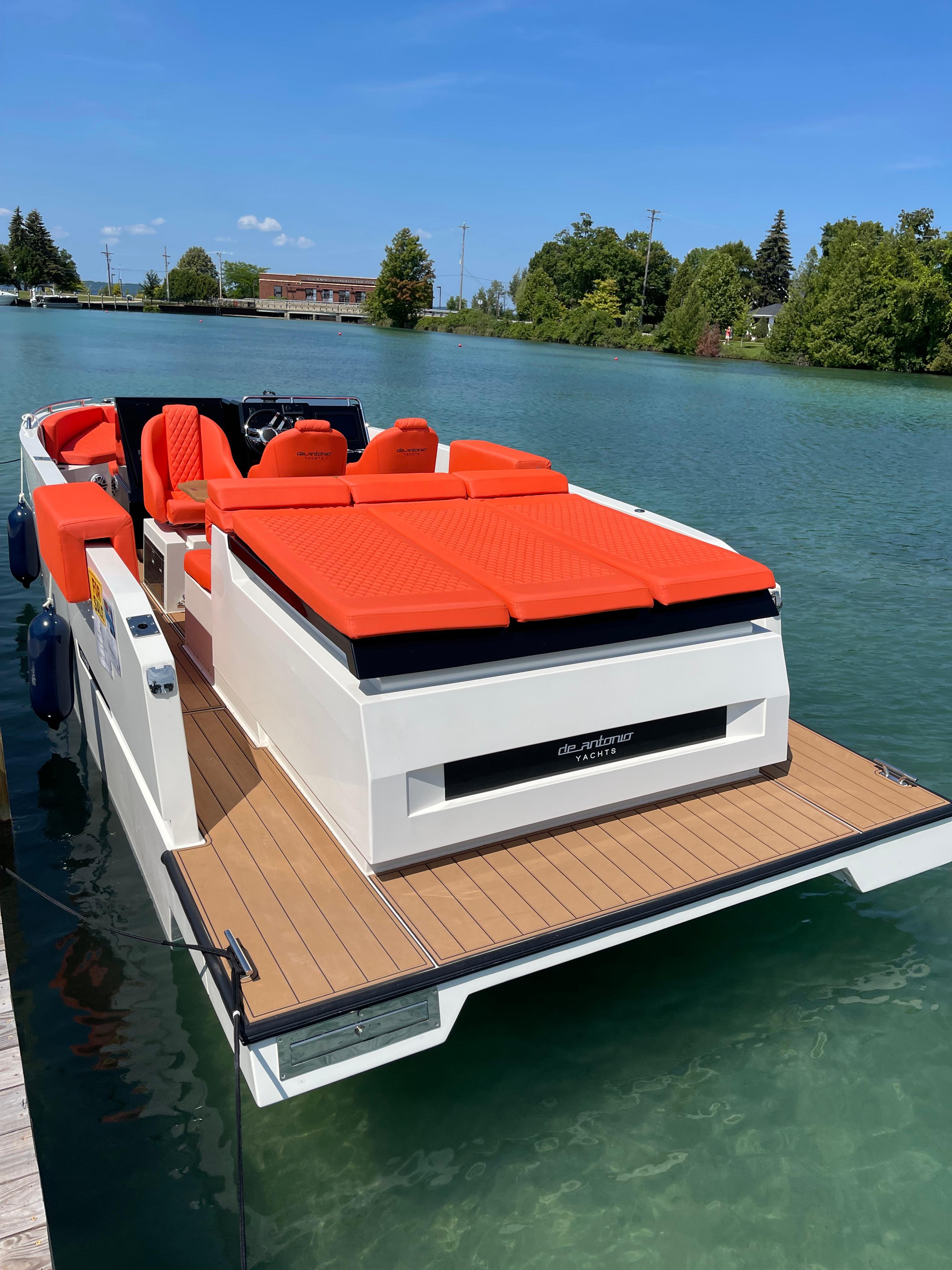 2020 De Antonio Yachts D 28 with vibrant orange seating on a serene lake.