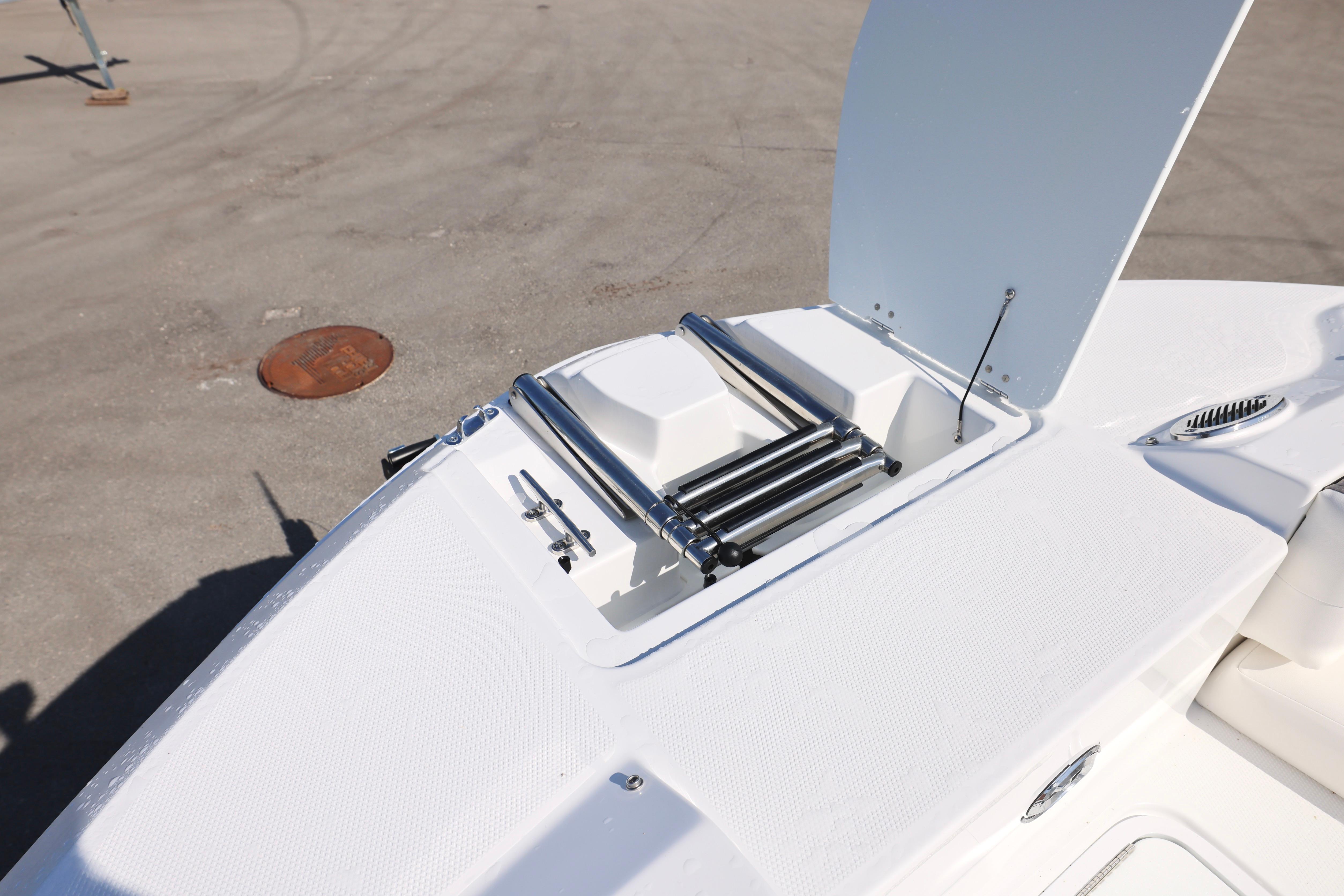 2026 Hurricane SunDeck 235 OB boat with open storage compartment and ladder.