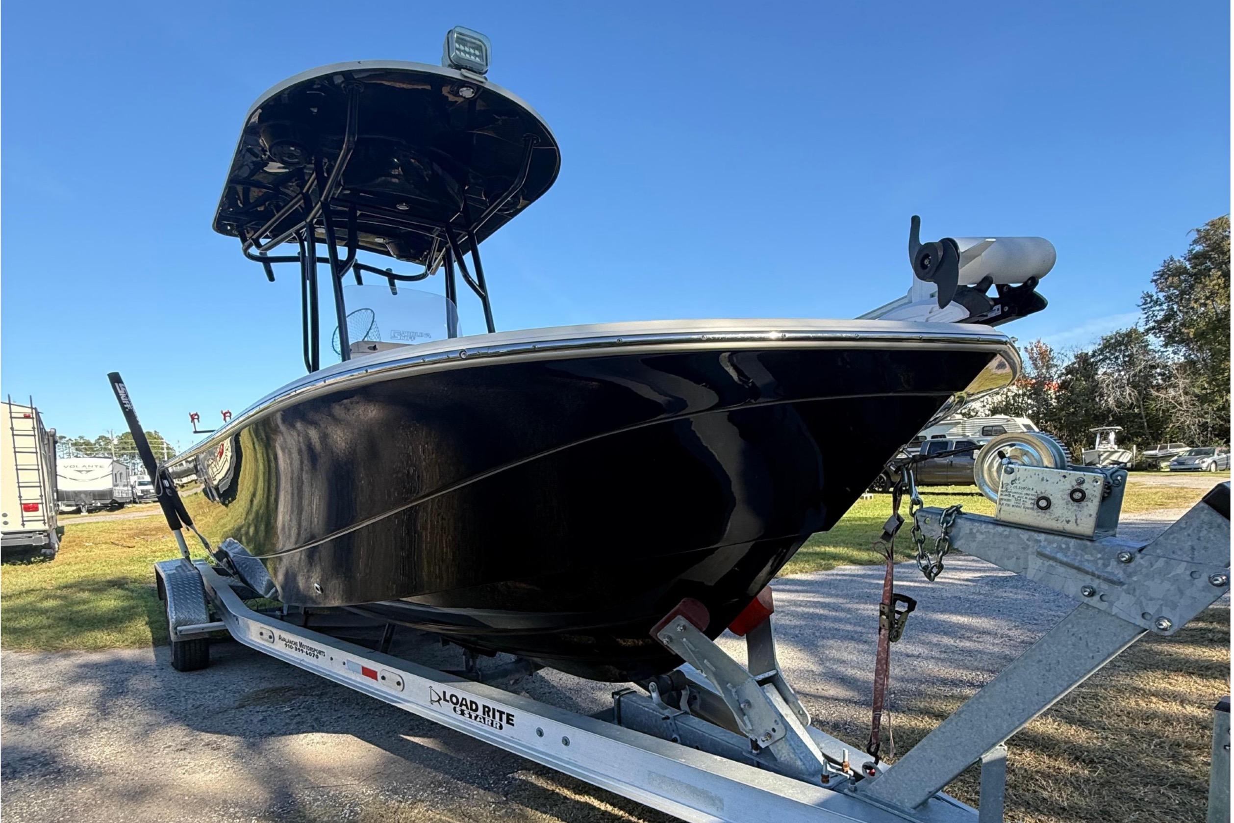 2021 Carolina Skiff 26 Ultra Elite boat on trailer, parked outdoors under clear blue sky.