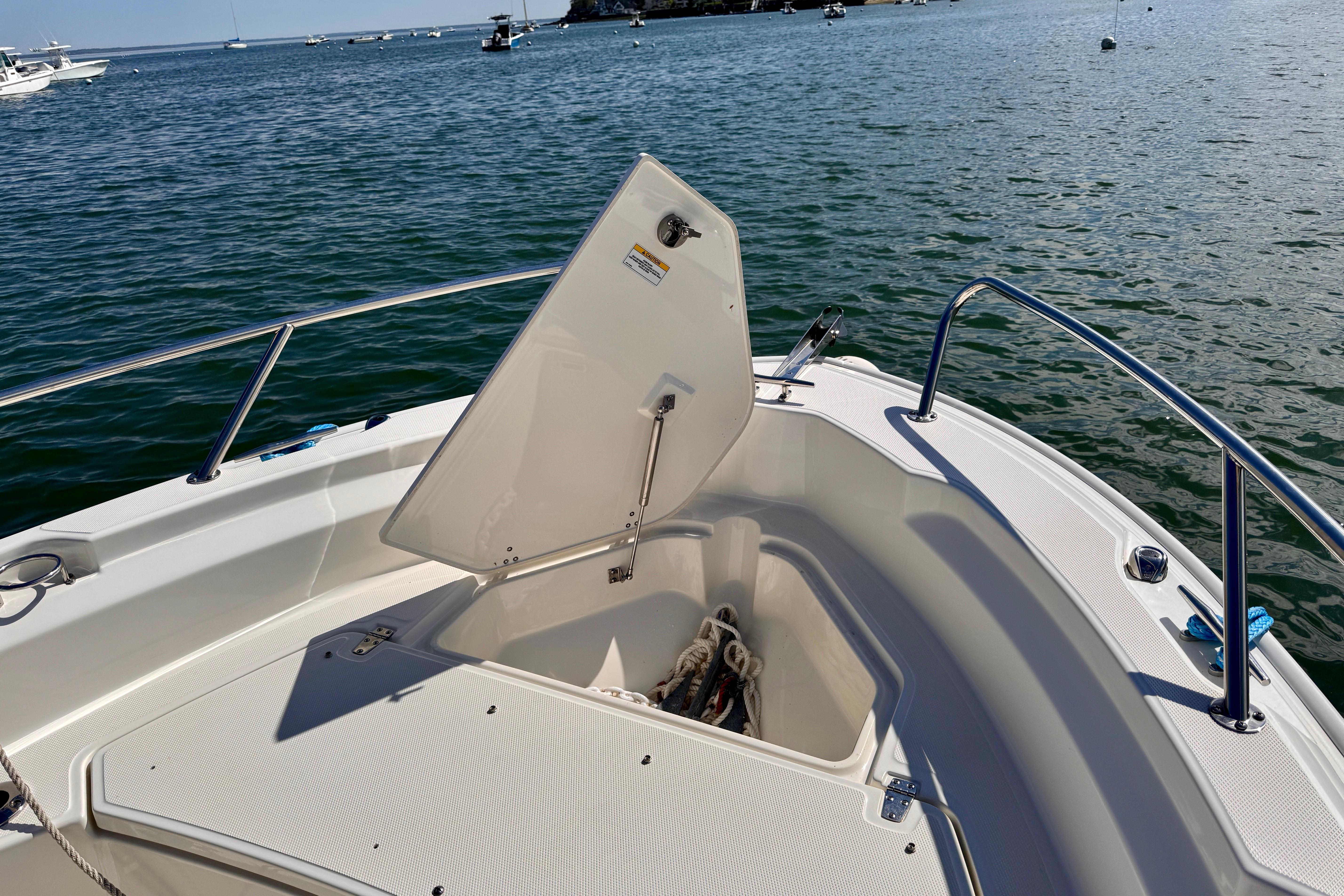2022 Boston Whaler 220 Dauntless boat with open storage compartment on calm water.